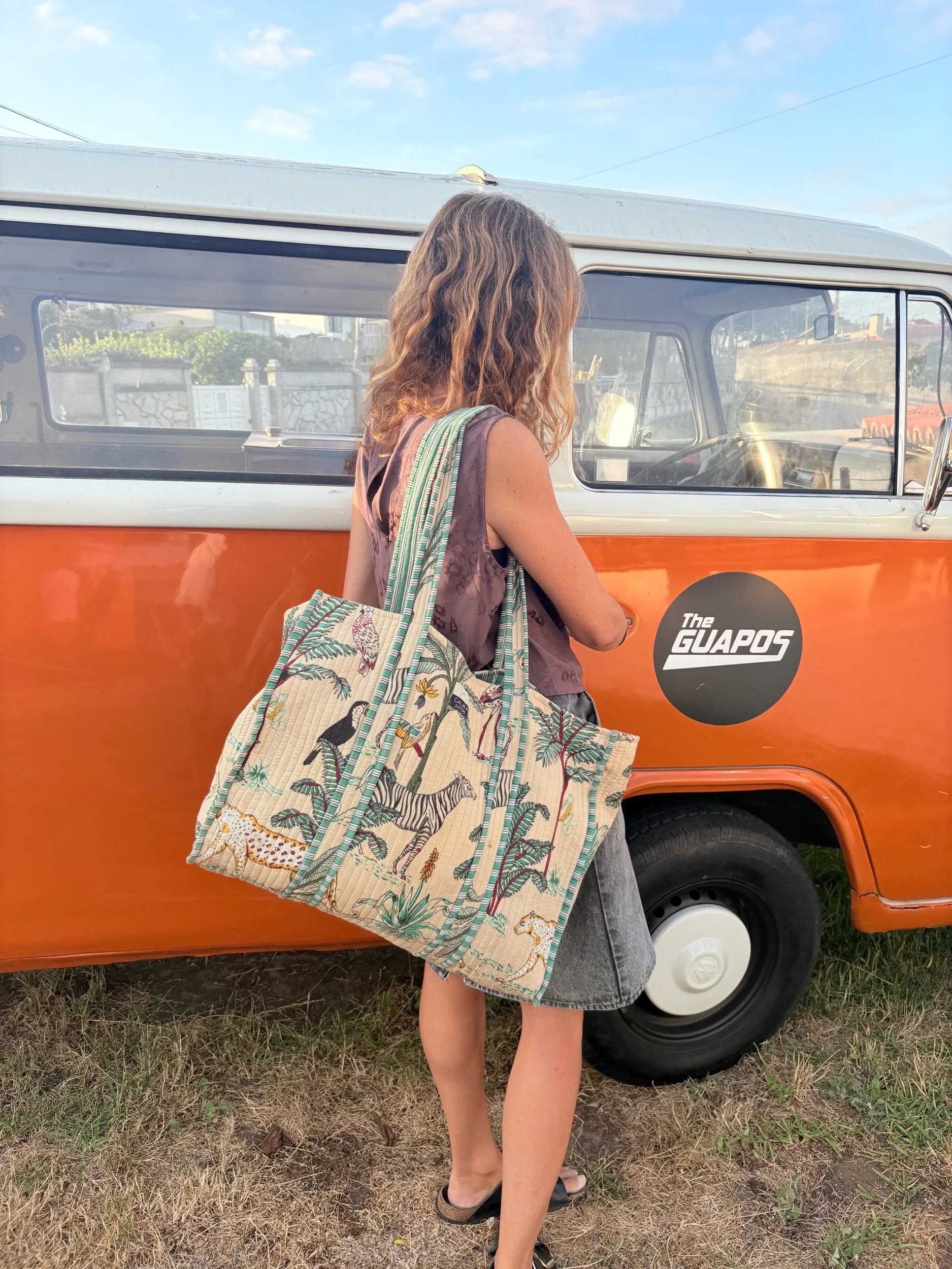 Mujer llevando una Bolsa TOTE reversible de algodón en tonos beige con estampado selva, asas anchas para llevar al hombro y bolsillo interior