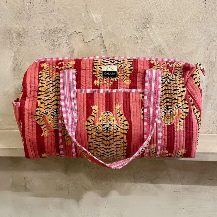Bolsa de mano rosa con estampado de tigres en tonos naranja, negro y blanco.