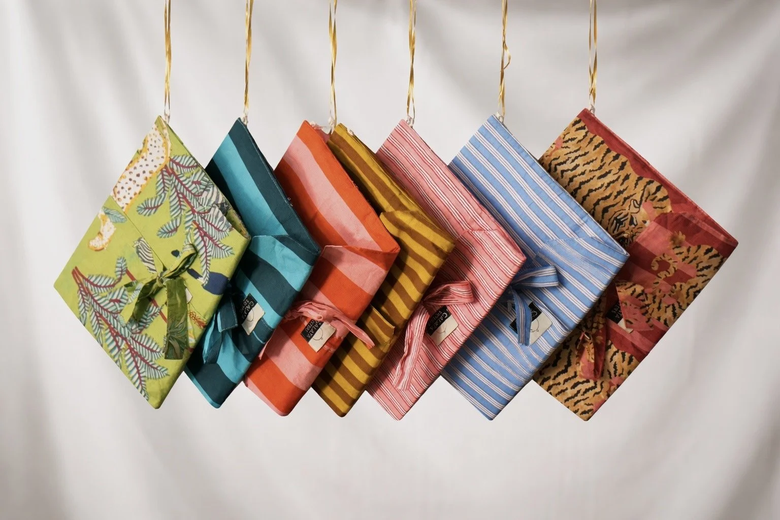 Paquetes envueltos en papel de regalo con diferentes colores y patrones, colgados por cintas doradas.