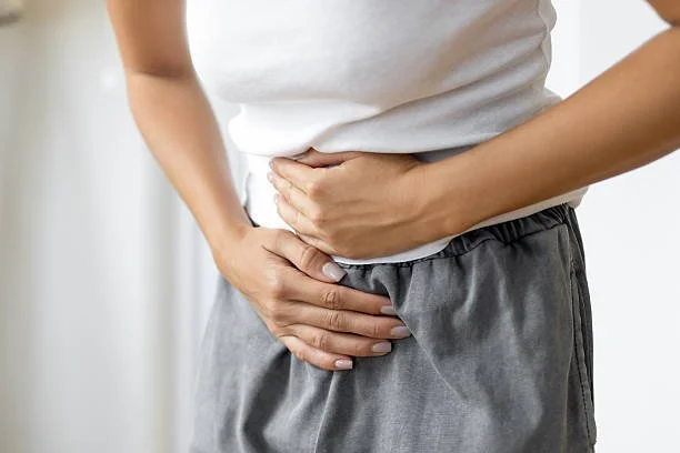 Person holding their side and stomach, appearing to experience pain or discomfort.
