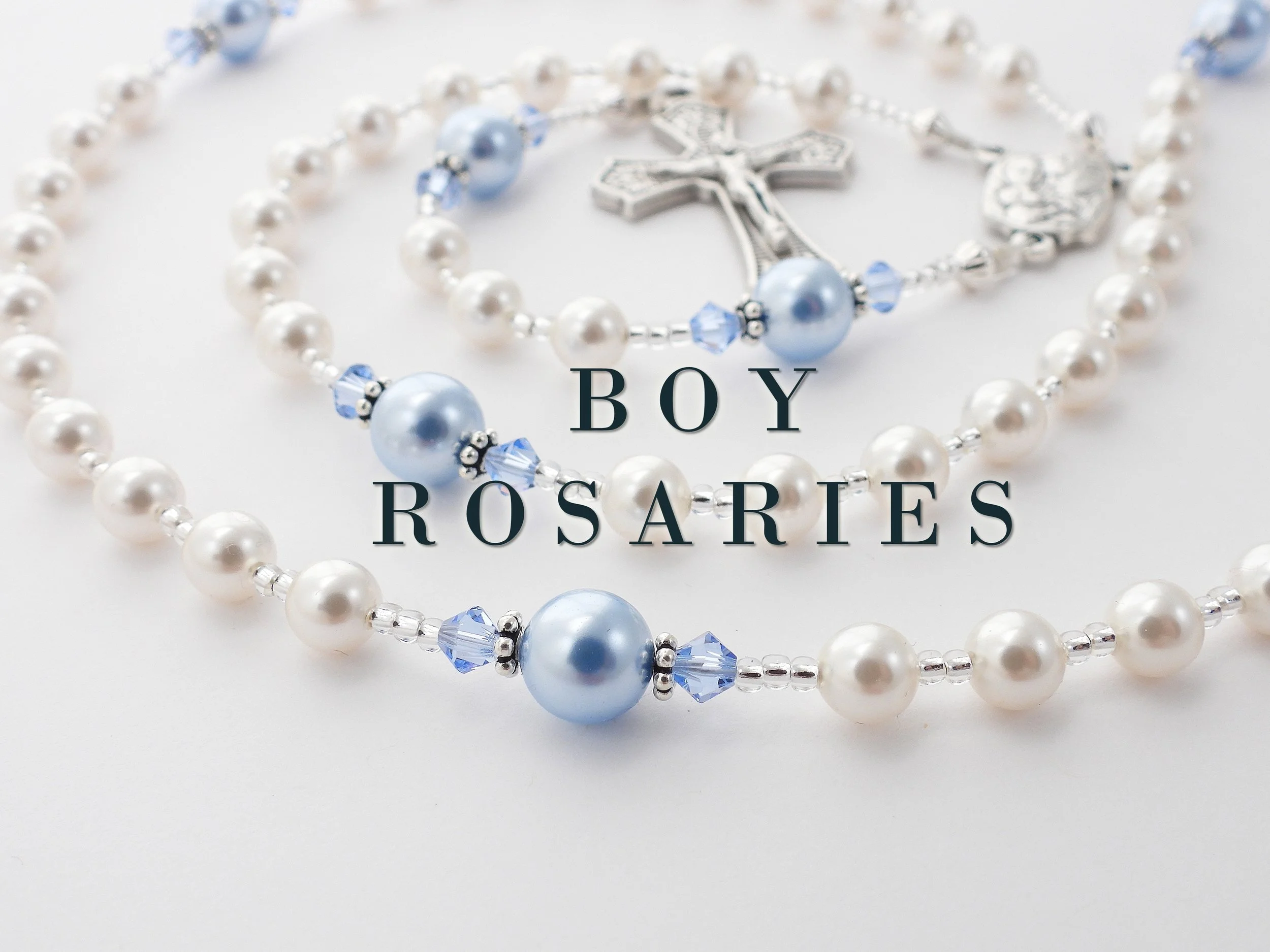 Close-up of pearl and blue beaded rosary with a silver crucifix, and the words "Boy Rosaries" printed on the image.