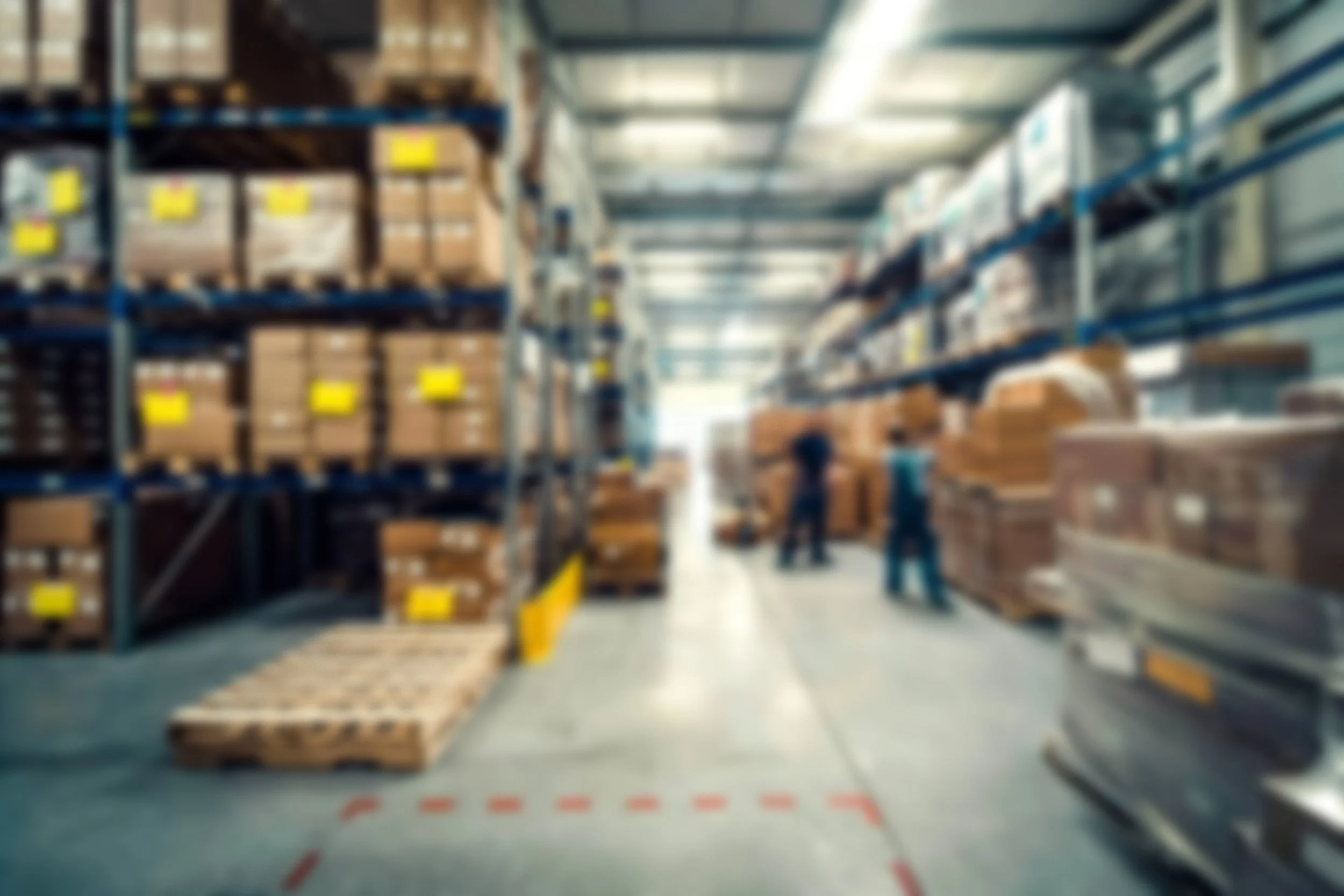 Almacén industrial con estanterías y cajas en efecto blur para fondo visual de sección web.