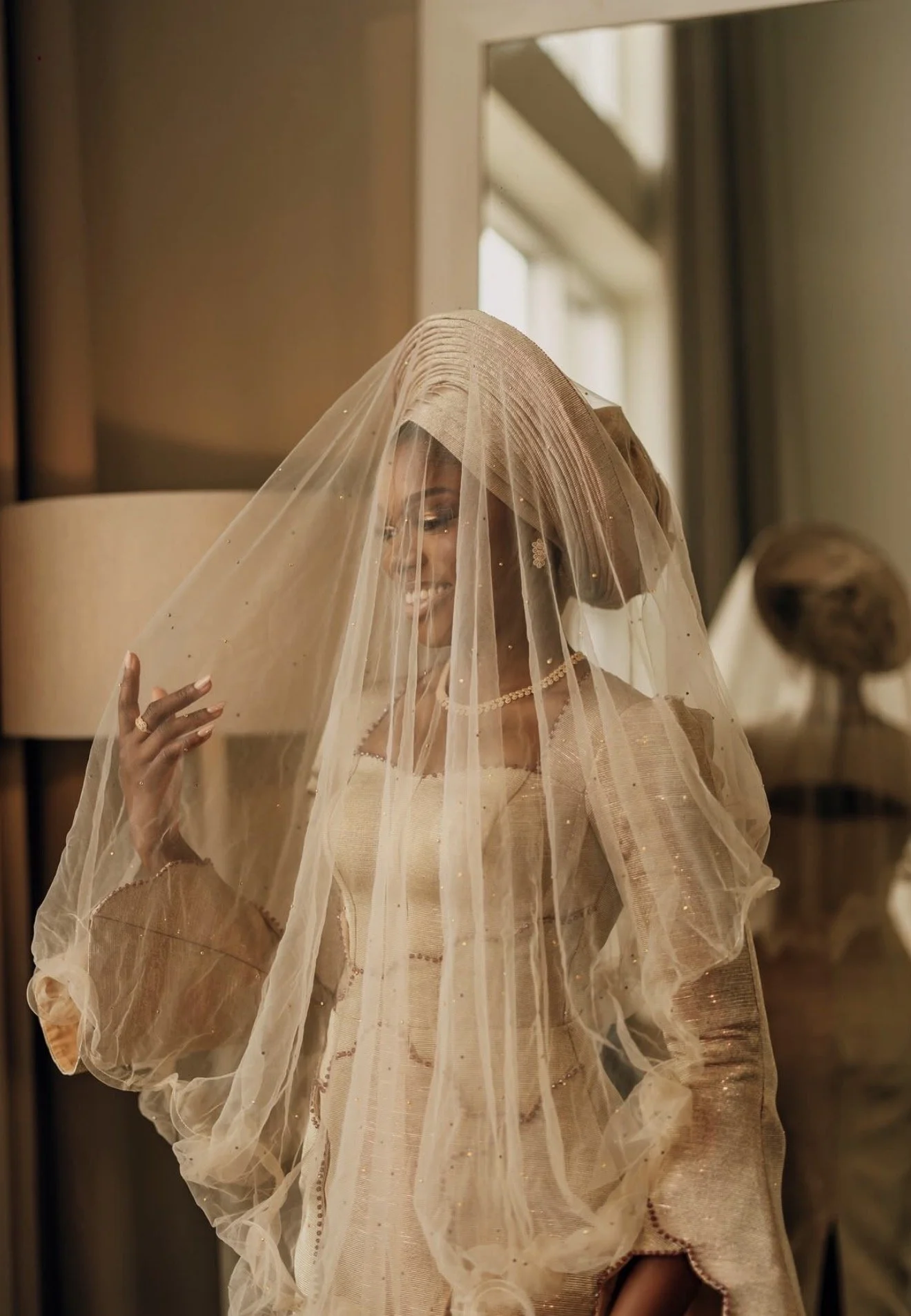 A couple dressed in traditional Nigerian attire, with the woman wearing purple and gold outfit and the man in purple agbada and cap, at a celebration or event.