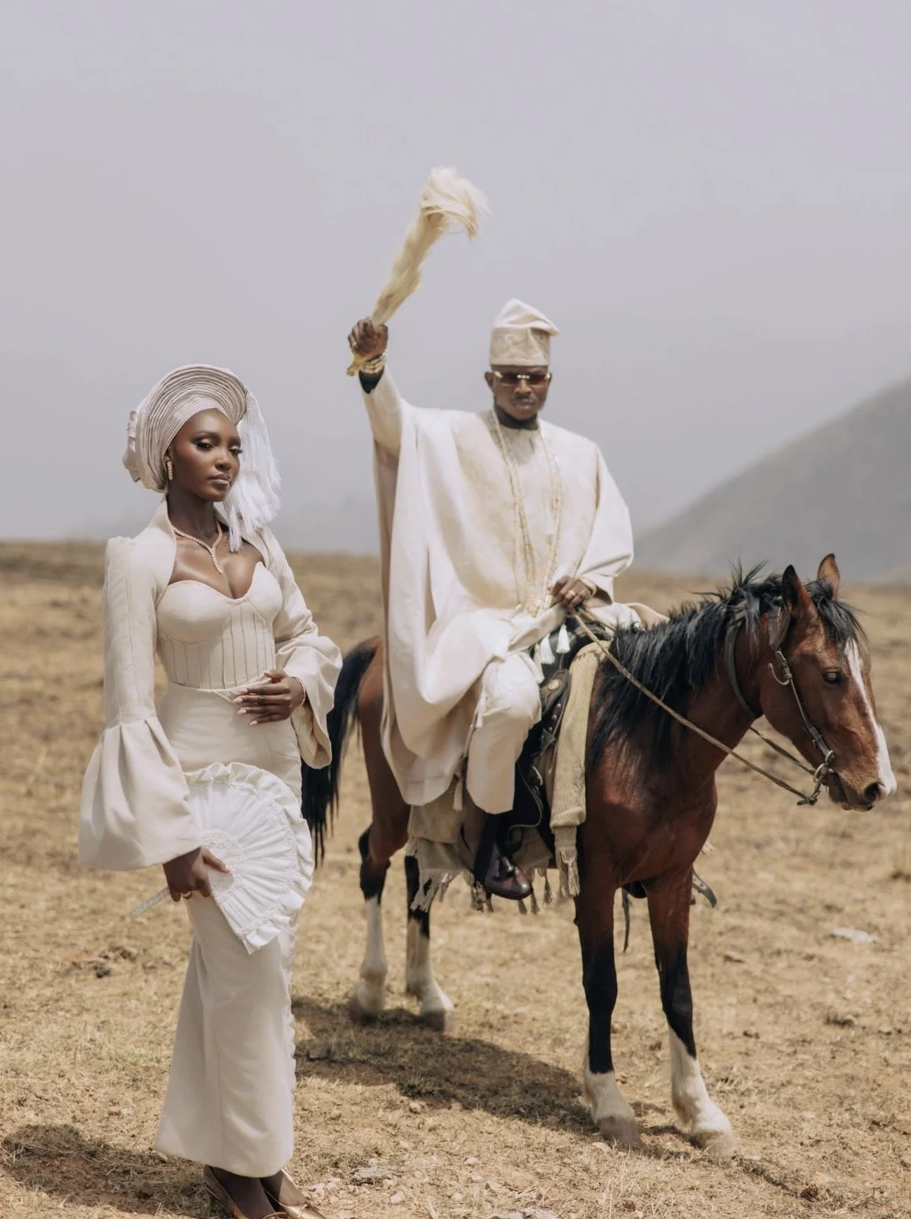 A joyful Nigerian couple dressed in traditional purple attire, surrounded by friends and family in colorful, festive clothing at a celebration or wedding.