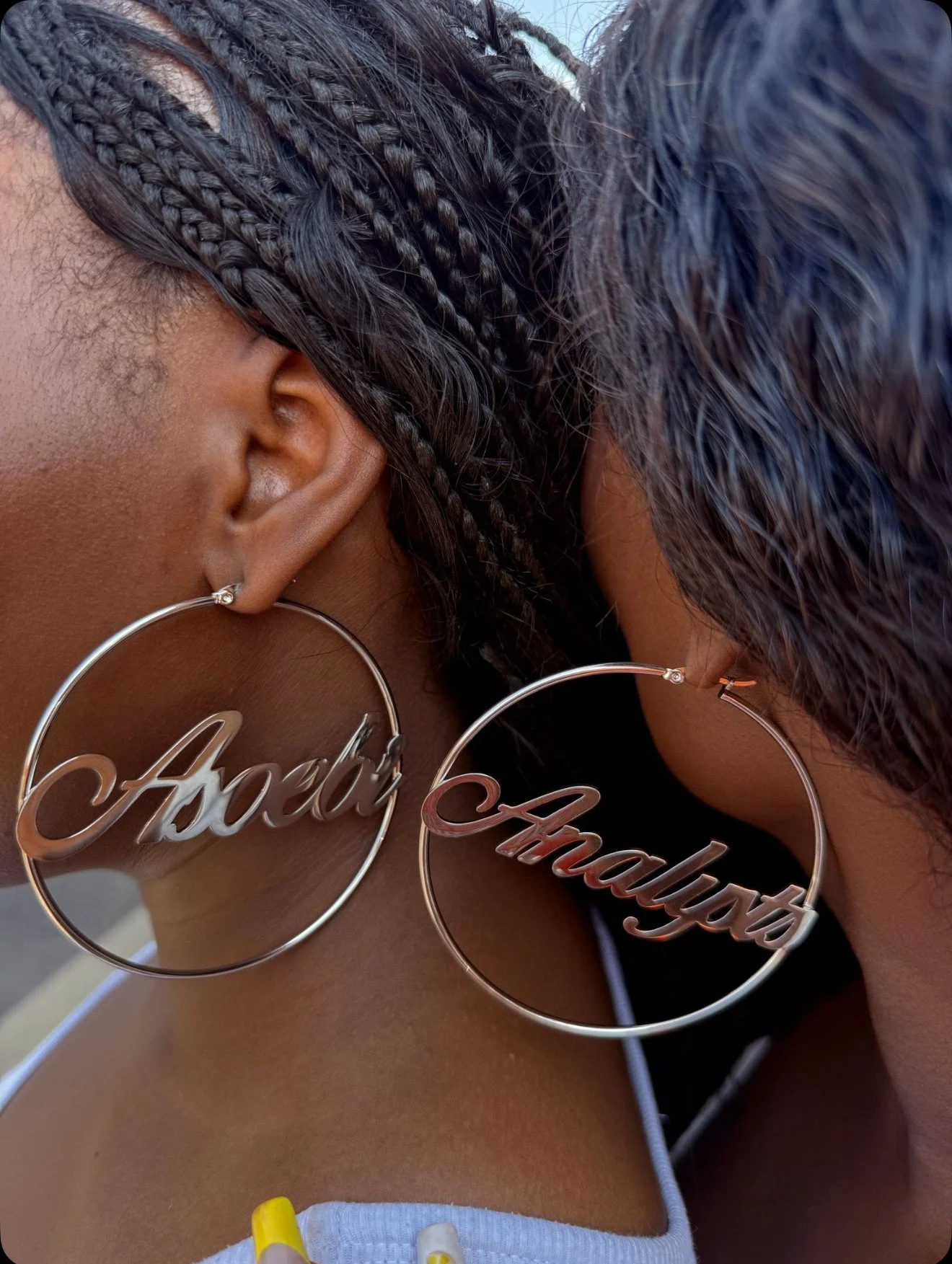 Close-up of two women wearing large hoop earrings with names, 'Ared' and 'Mady', their faces close together.