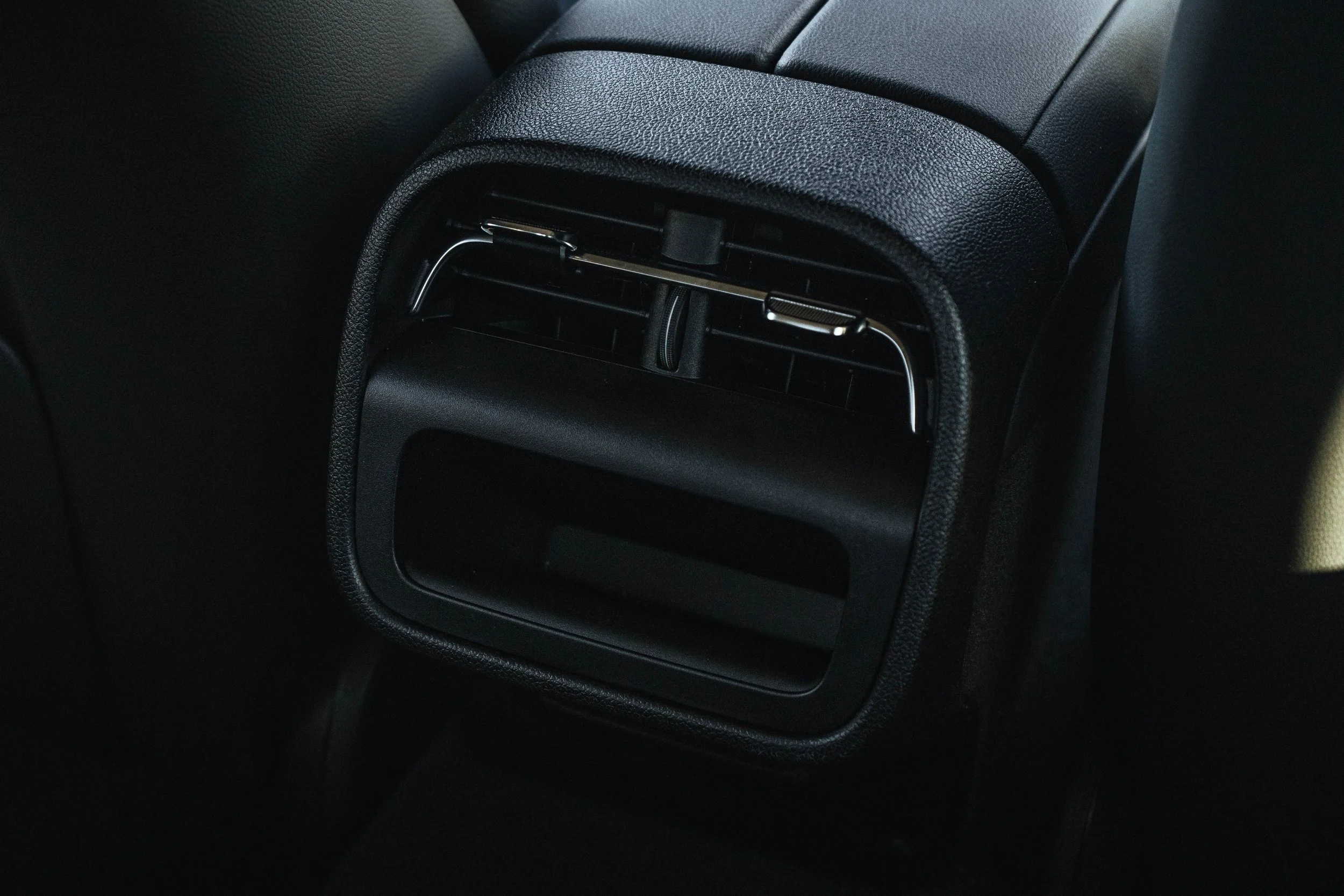 Vents de ar condicionado do carro com acabamento preto e textura fosca.