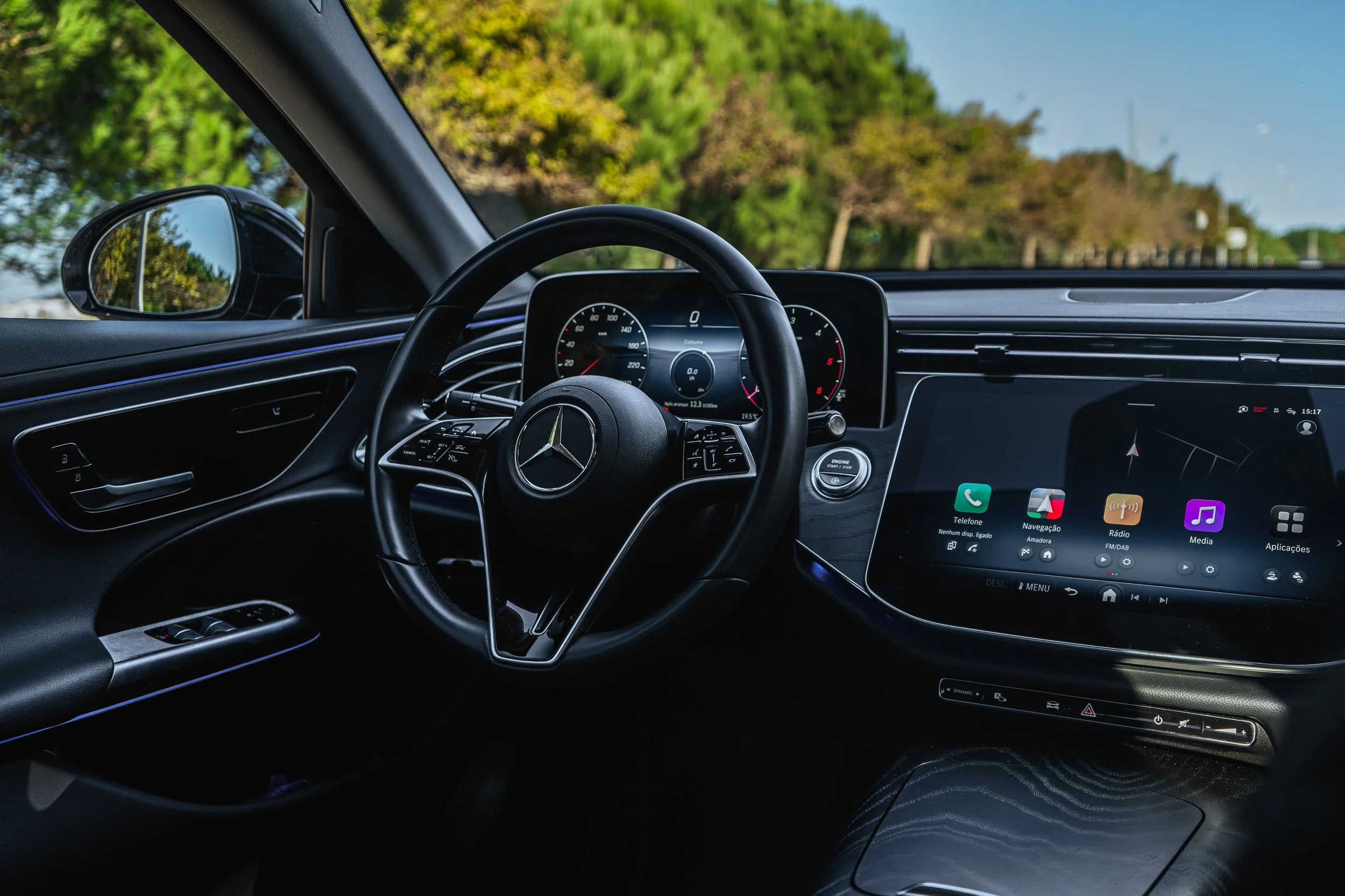 Interior de carro Mercedes-Benz com painel digital e tela de navegação, volante com logo da Mercedes-Benz