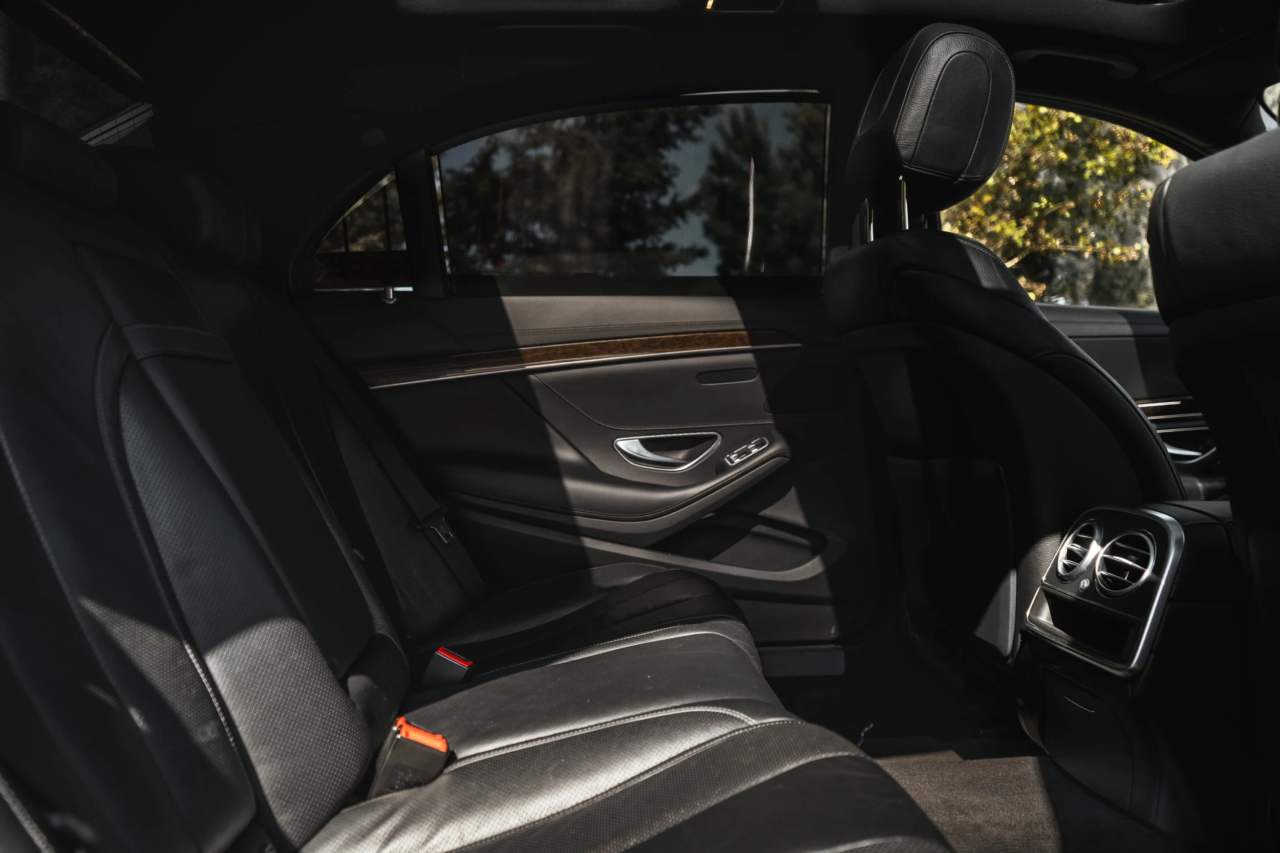 Interior de carro com assentos de couro preto e saídas de ar no painel traseiro.