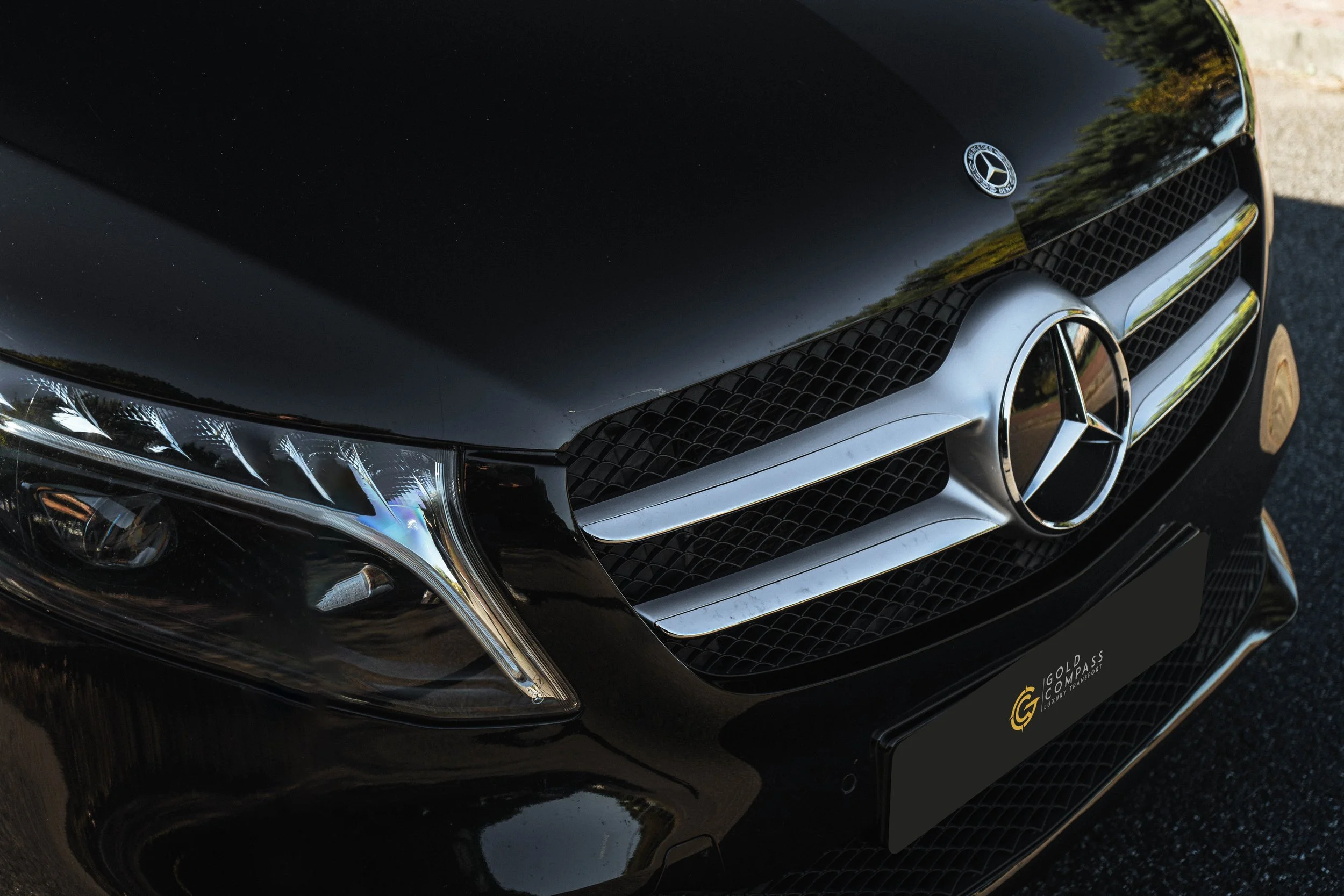 Frontal de carro preto Mercedes-Benz, capô, grade dianteira, logotipo e faróis.
