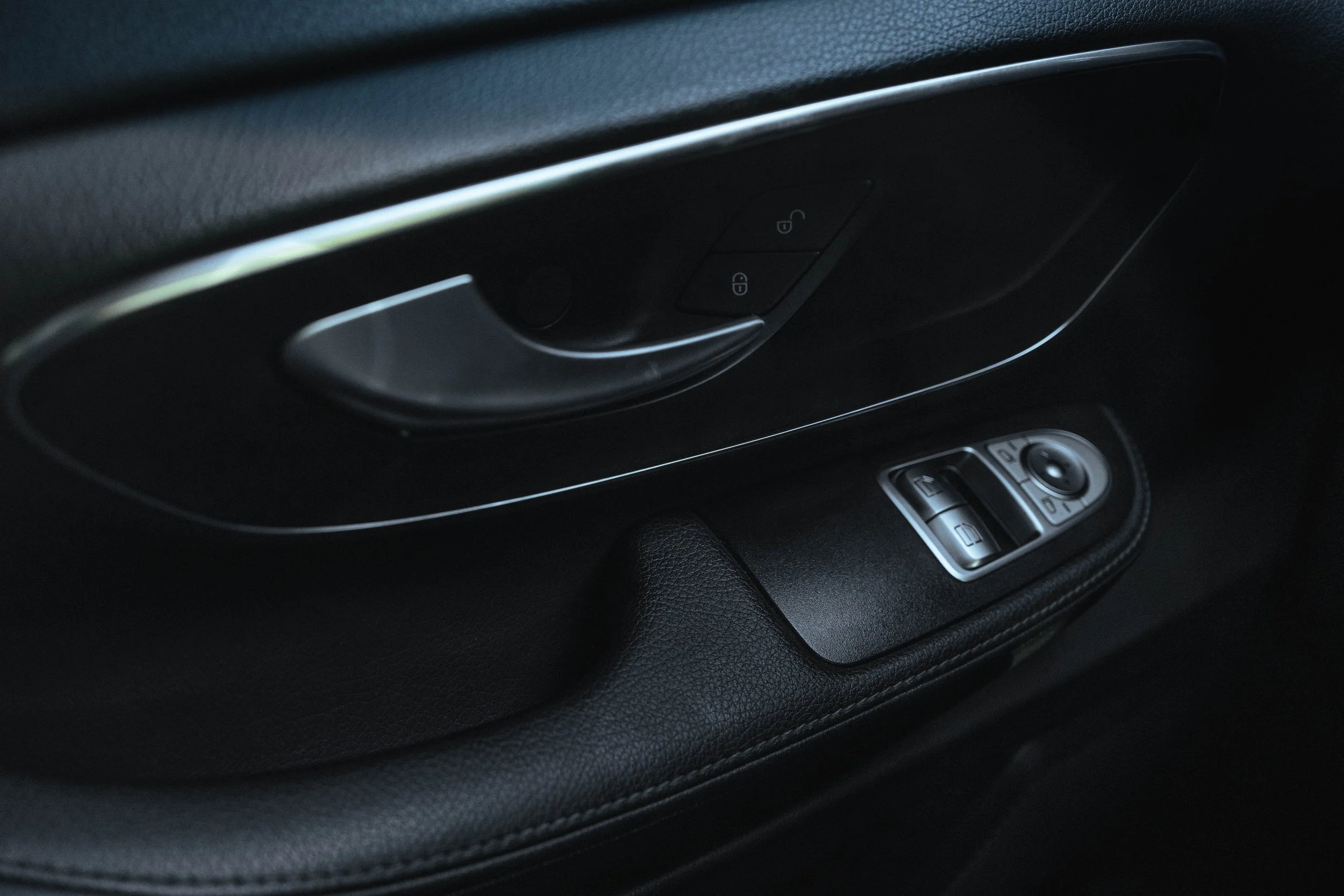 Painel de controle da porta de um carro com botão de trava e abertura, e controles de janelas e espelhos side mirror.