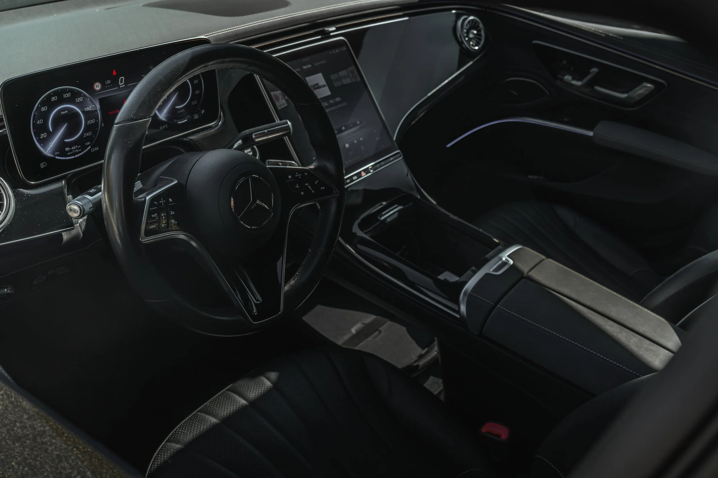 Interior de carro de luxo Mercedes-Benz, destacando o painel digital, volante com logo da marca e console central com tela touch.