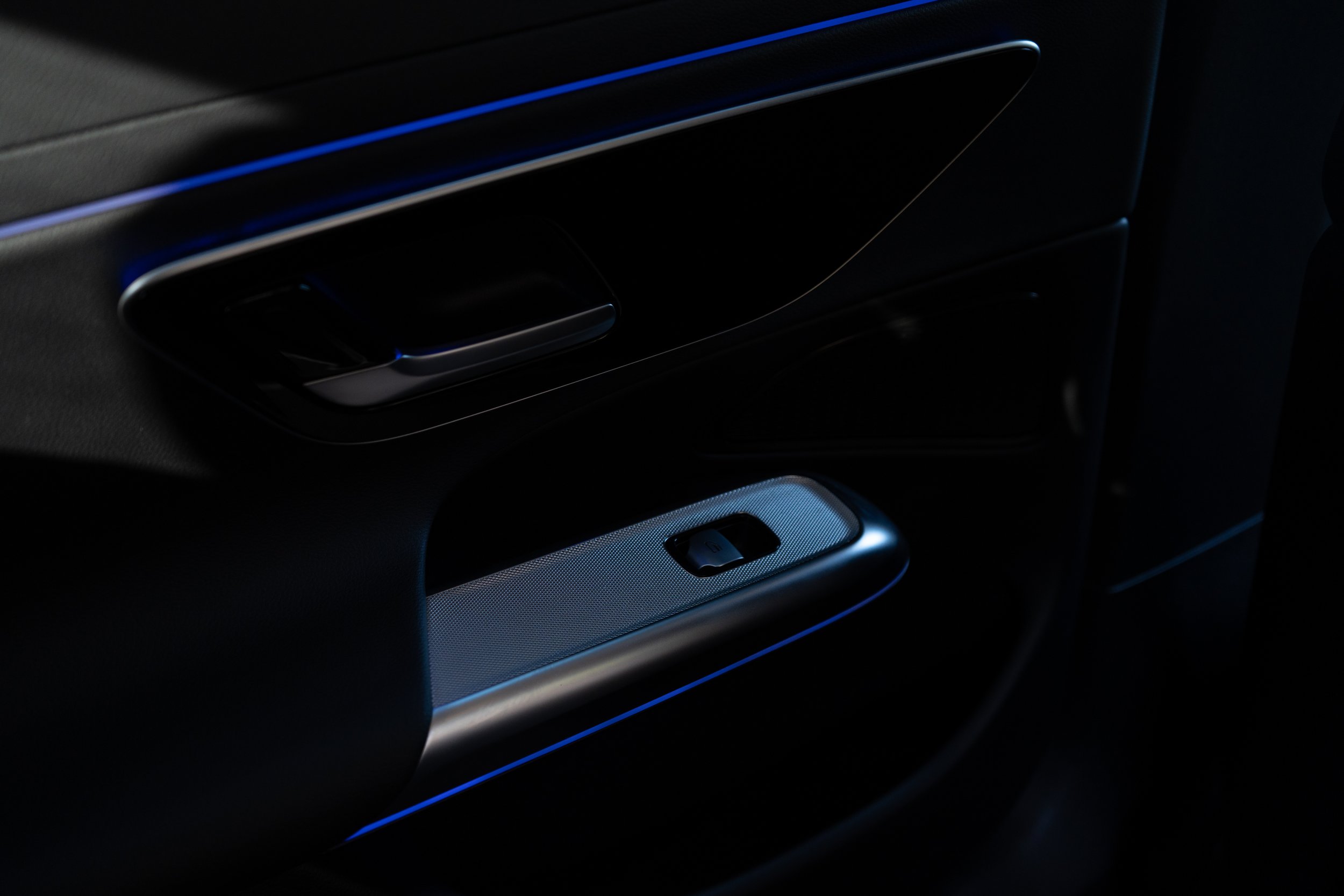 Interior de carro escuro com uma porta e uma janela com iluminação azul