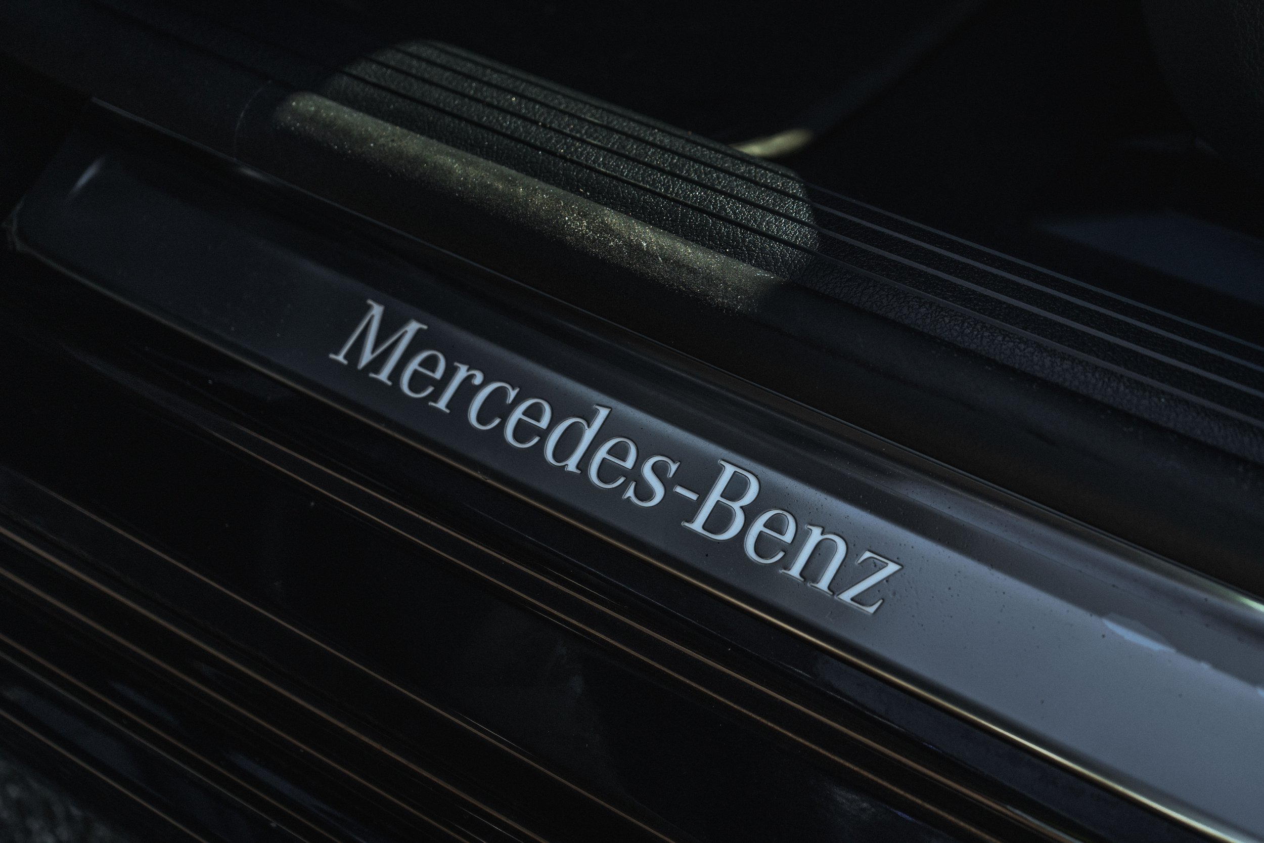 Relevo de um batente de porta com a marca Mercedes-Benz escrita em destaque.