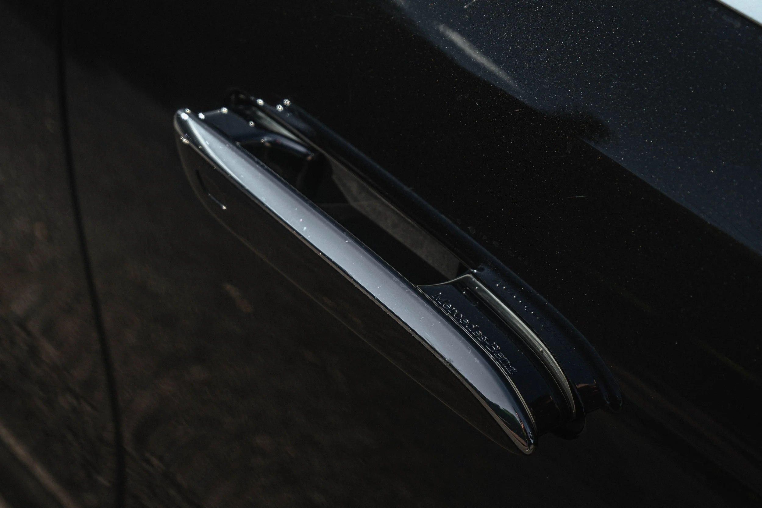 Fecho de porta de carro Mercedes-Benz na cor preta, com detalhes cromados.