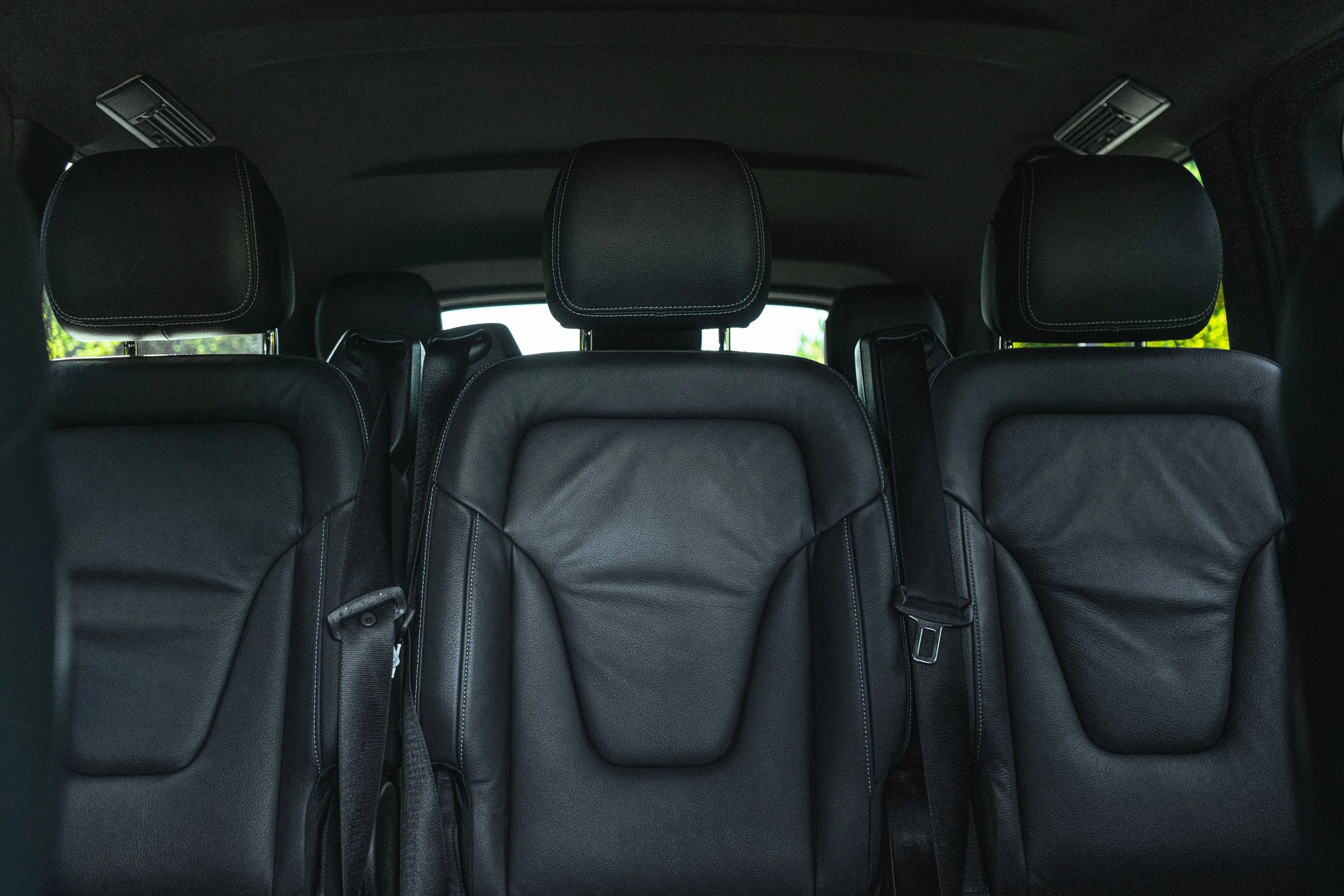 Assentos de carro de couro preto na parte traseira de um veículo.