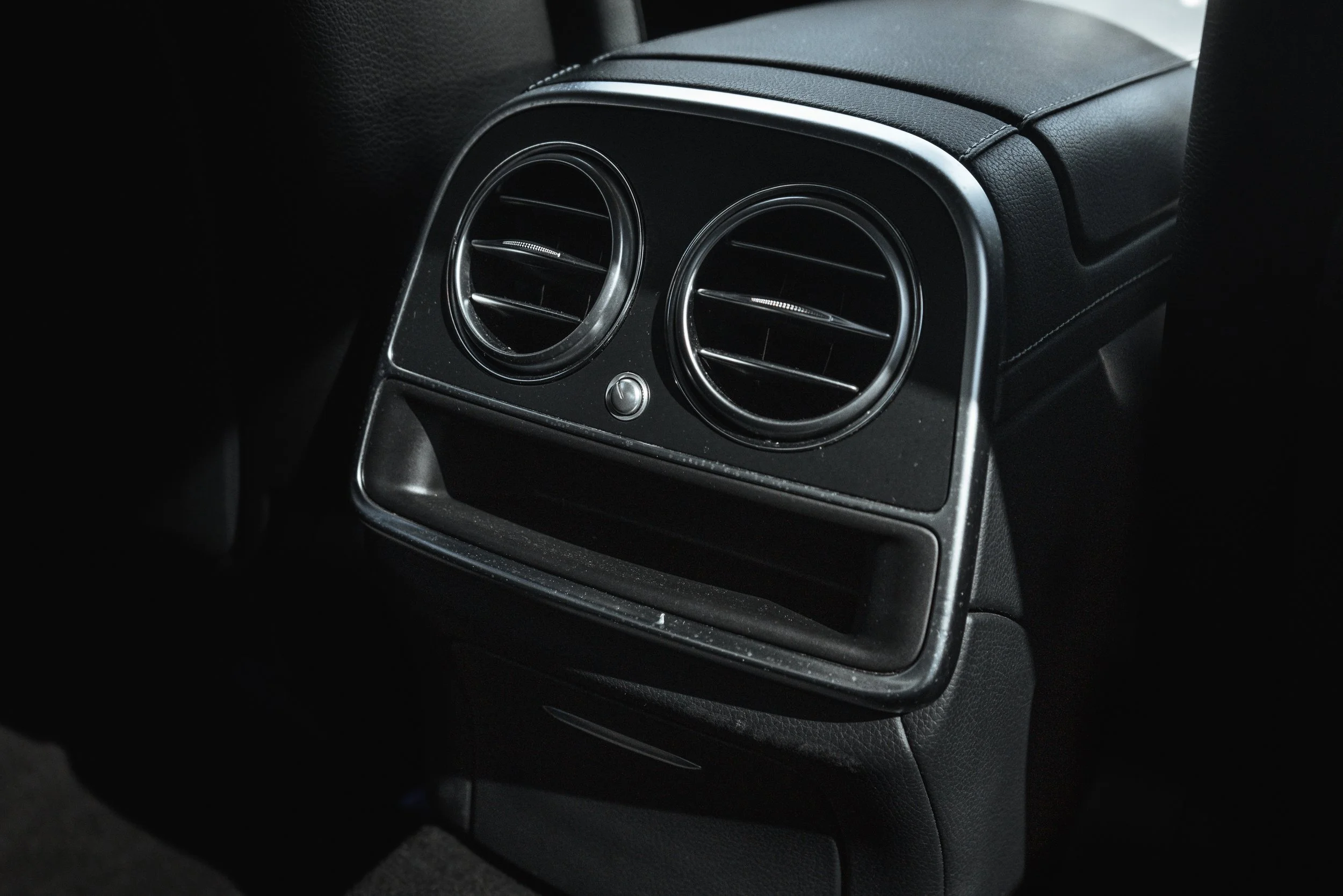 Ventos de ar do carro na parte traseira do veículo com painel preto e detalhes em prata.