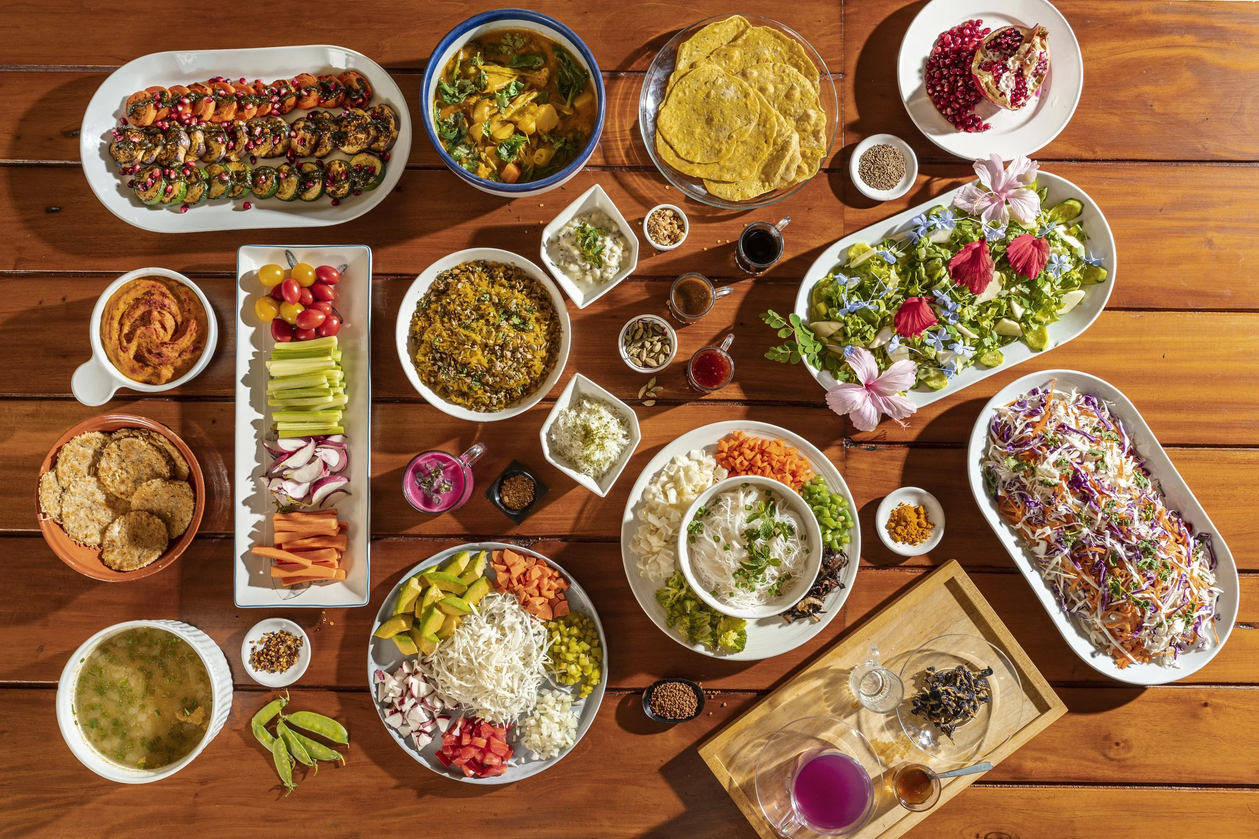 A variety of colorful Mexican dishes on a wooden table. Includes tacos, salads, sauces, dips, and fresh vegetables.