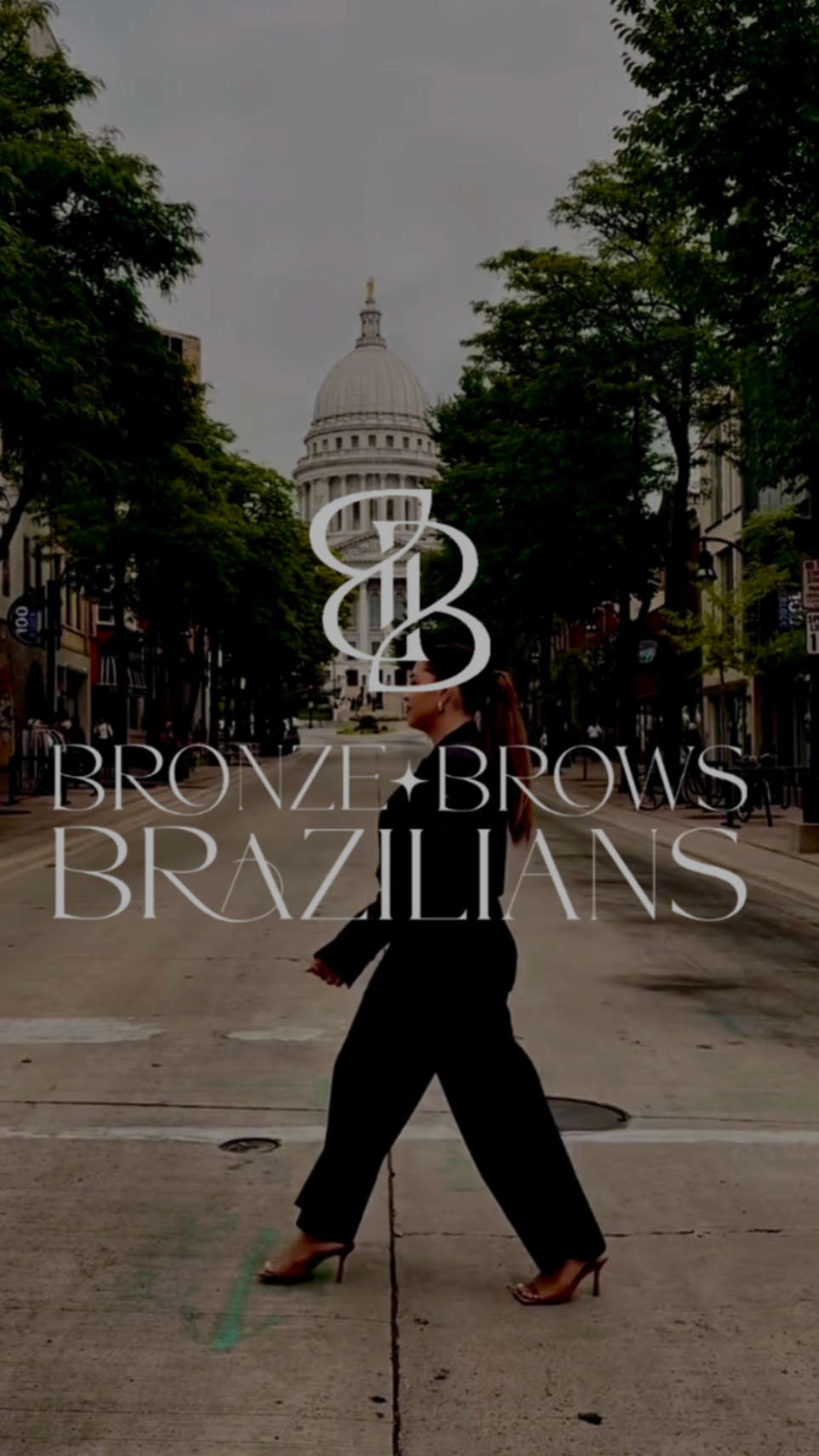 A street scene with trees and the state capitol in the background. A woman in black high heels, with long hair tied back, is walking across the street. The words 'Bronze Brows Brazilians' are overlayed on the image.