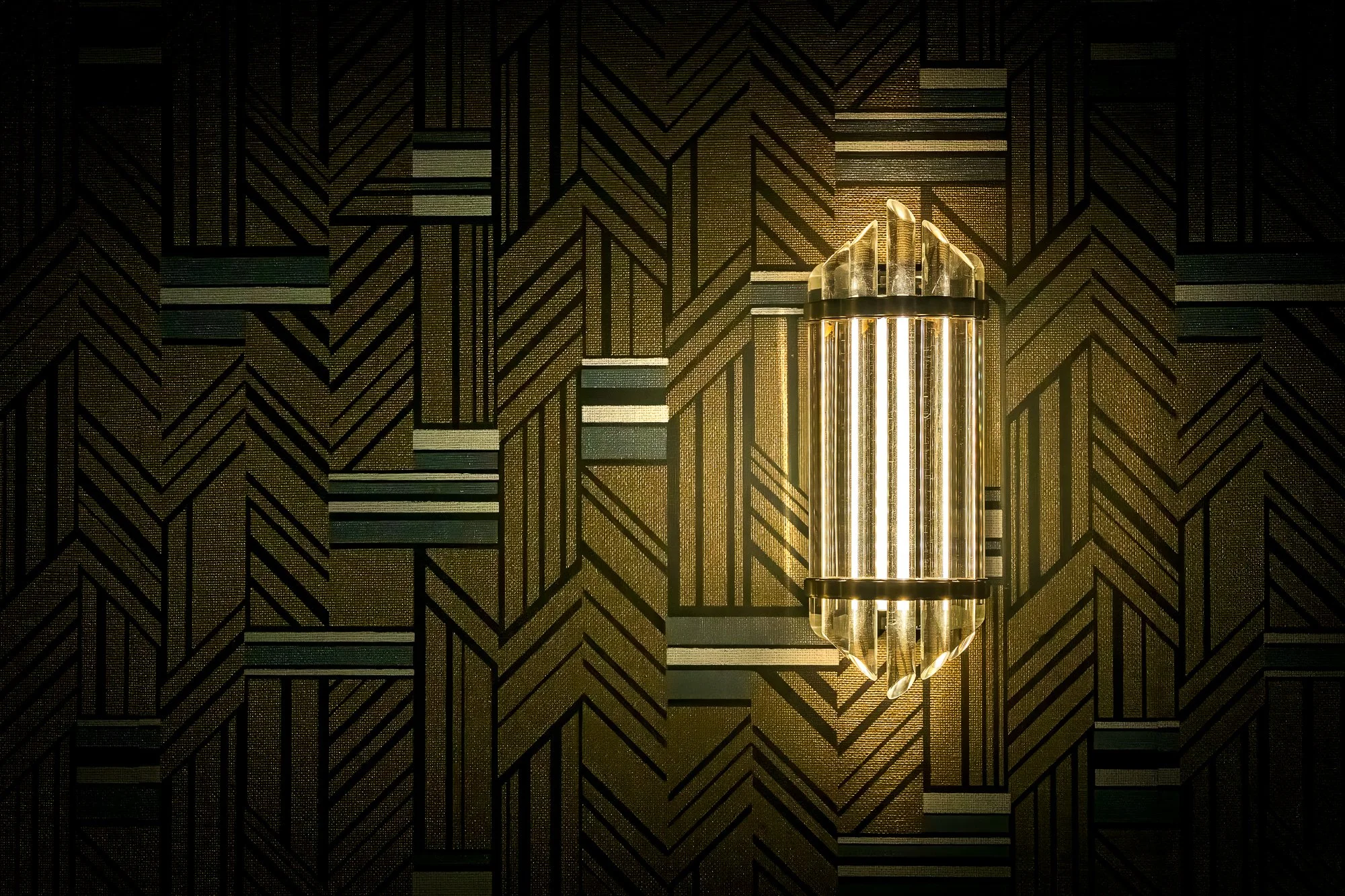 Art Deco-style wall sconce glowing against geometric patterned wallpaper inside The Floridian Social.