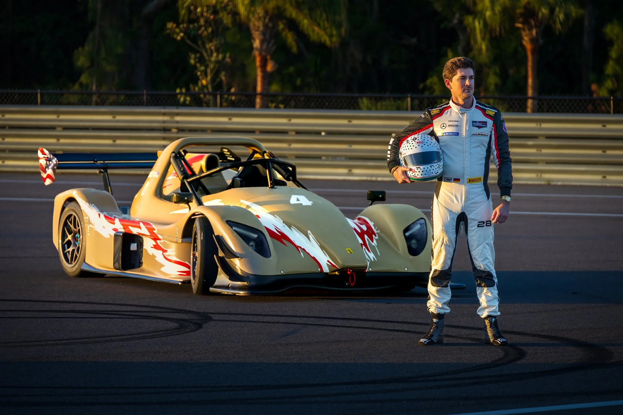 Driver standing beside a race car on the track at sunrise at The Motor Enclave in Tampa, Florida.