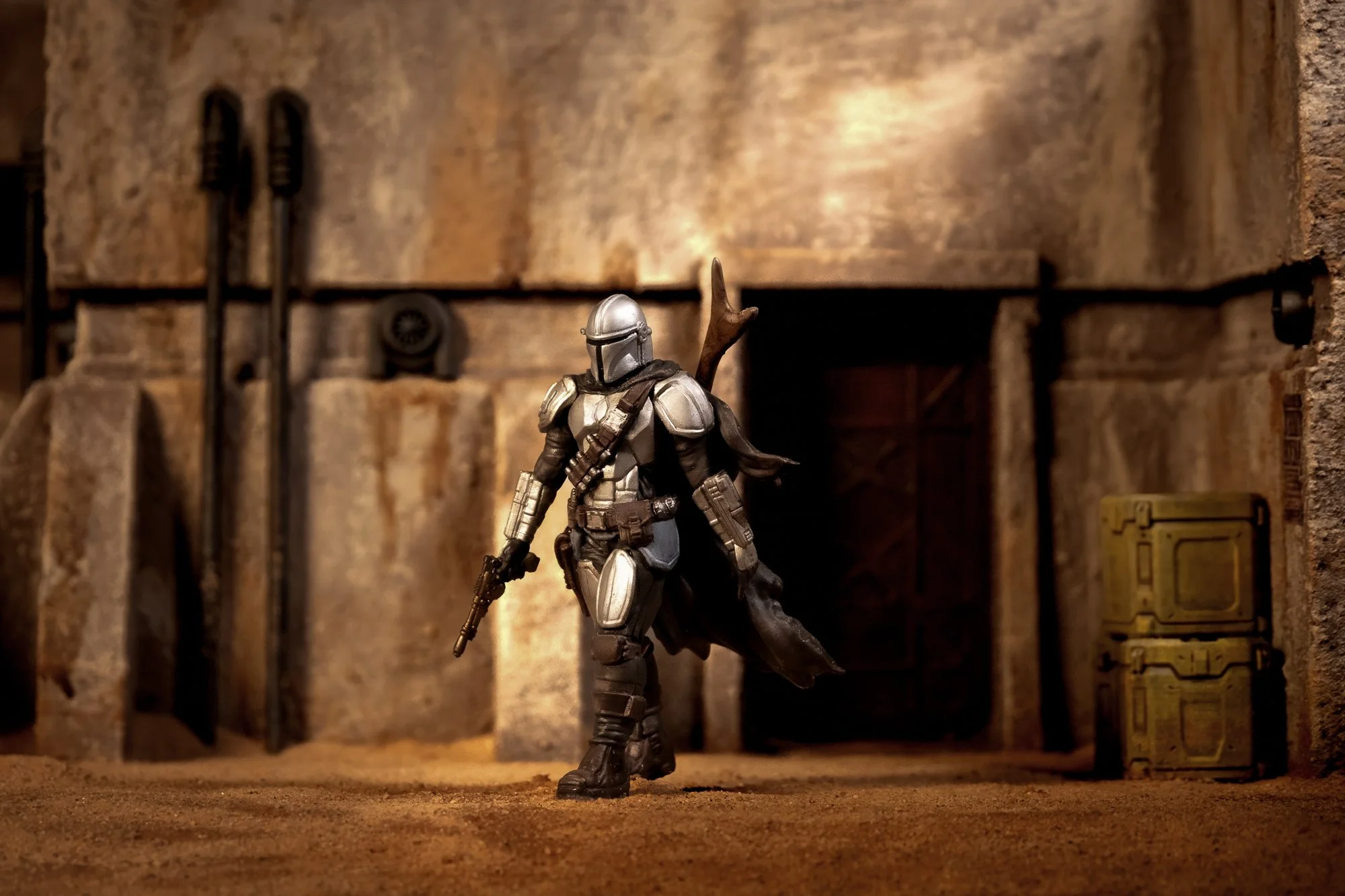 Miniature studio photograph of an armored sci-fi figure standing in a warm, weathered set with shallow depth of field and cinematic lighting.