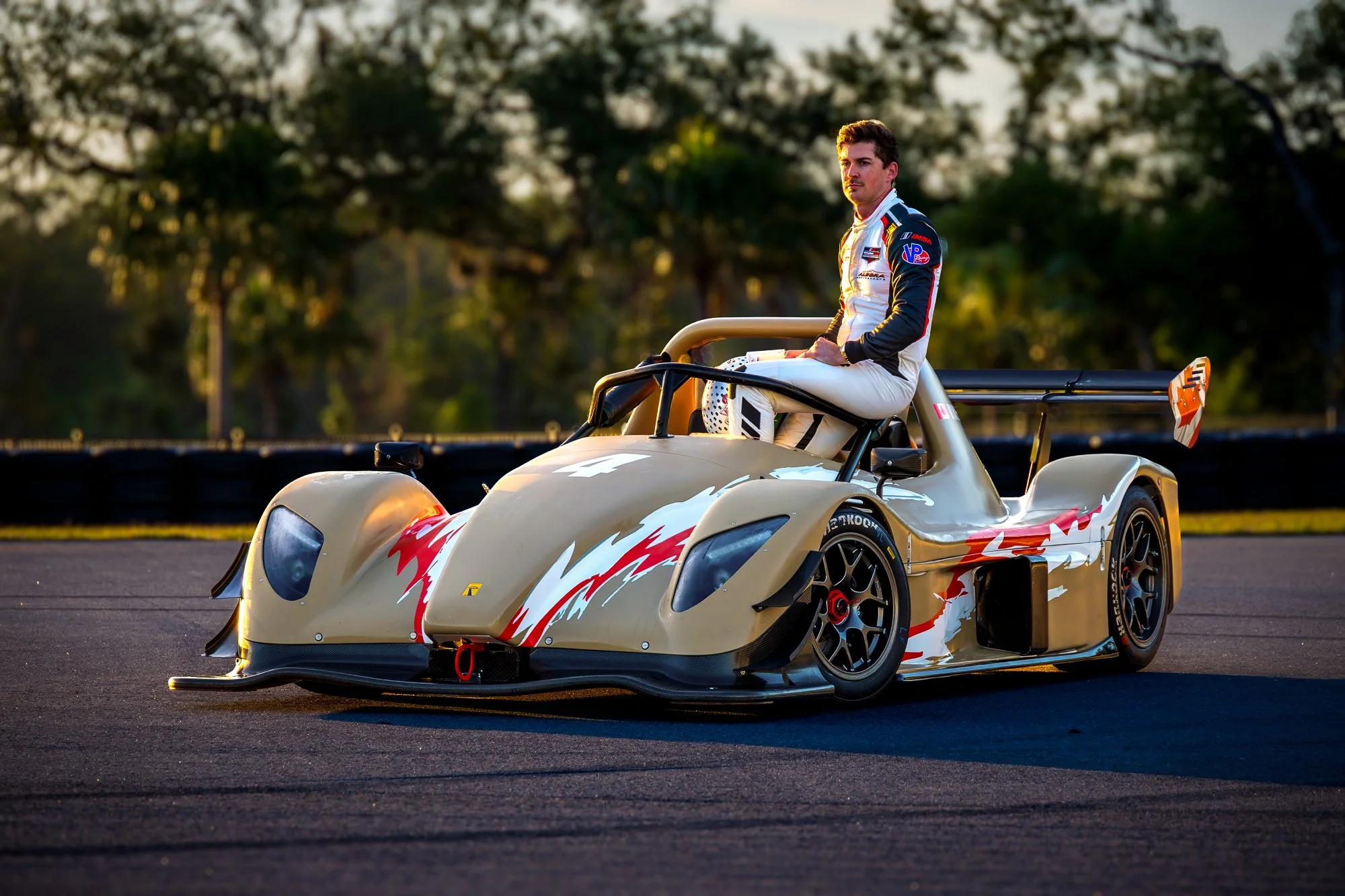 Driver seated on a race car during sunrise at The Motor Enclave motorsports campus in Tampa.