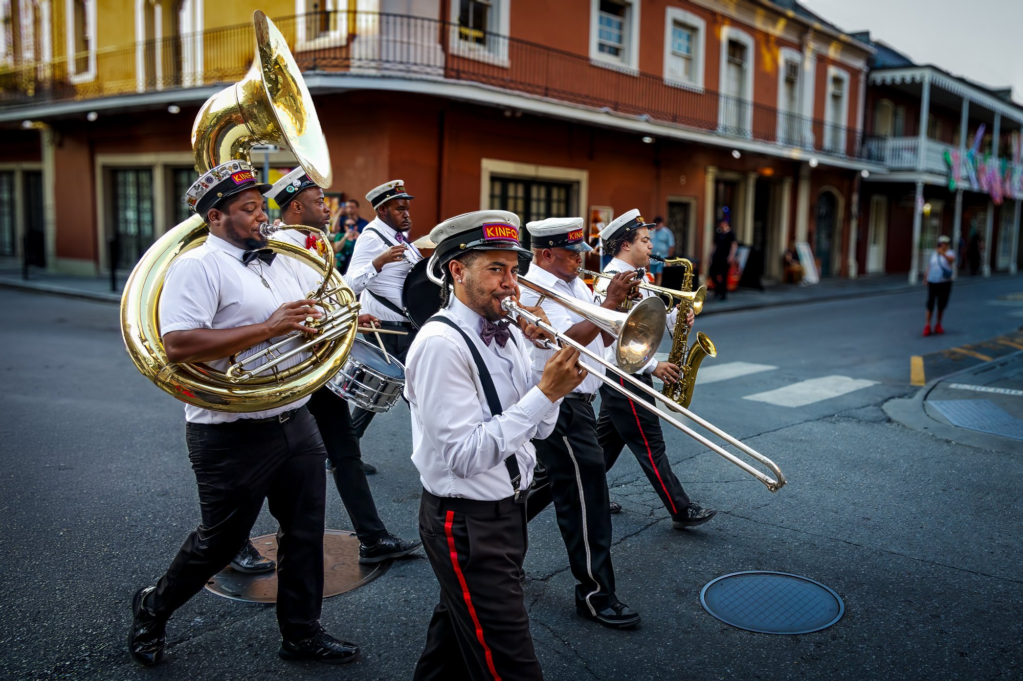 Brass musicians, KINFOLK, in white shirts perform during a New Orleans second line parade on a French Quarter street.