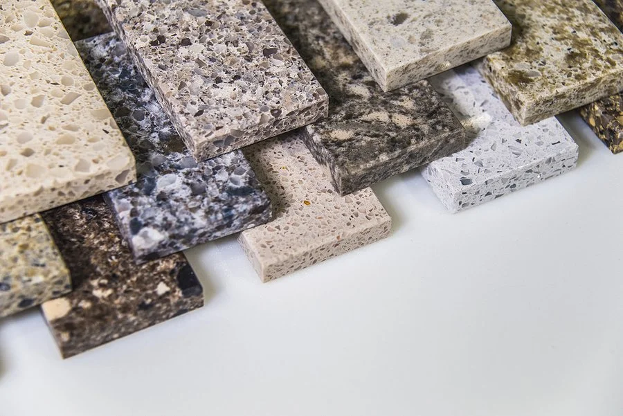 Assorted stone countertop samples arranged on a clean white surface.
