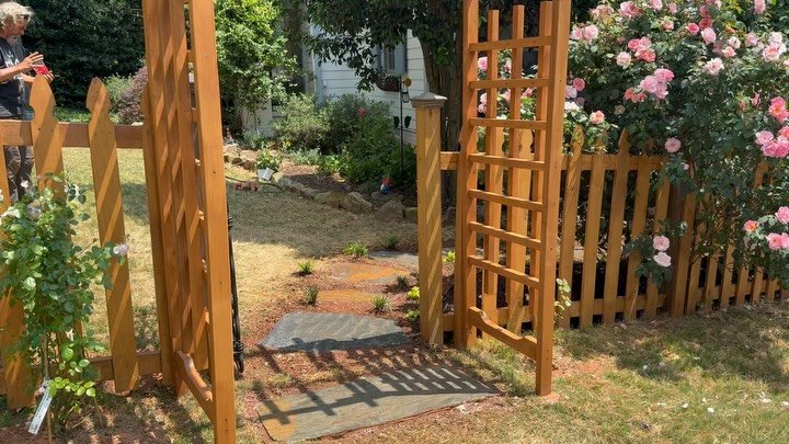 New fence, gate and pergola, flagstone path with plantings. Client wanted to incorporate a wrought iron gate so we constructed and stained a pergola to match the new fencing. Her pink roses were protected and highlighted for this natural, English gar