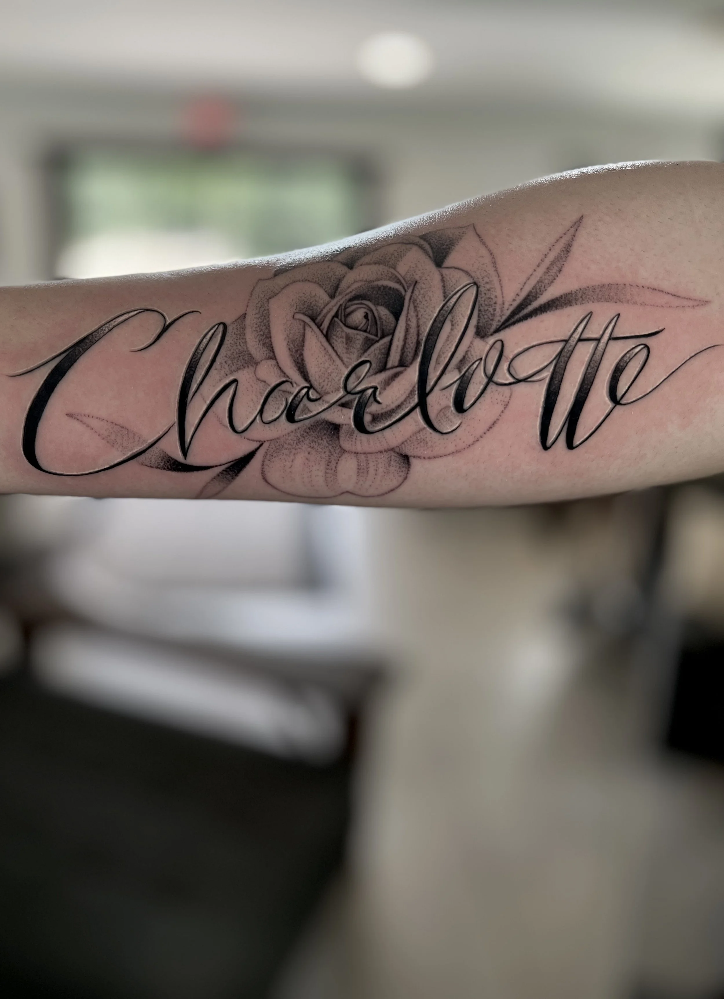 Tattoo of a rose with the words 'Chloe & Otto' in cursive script.