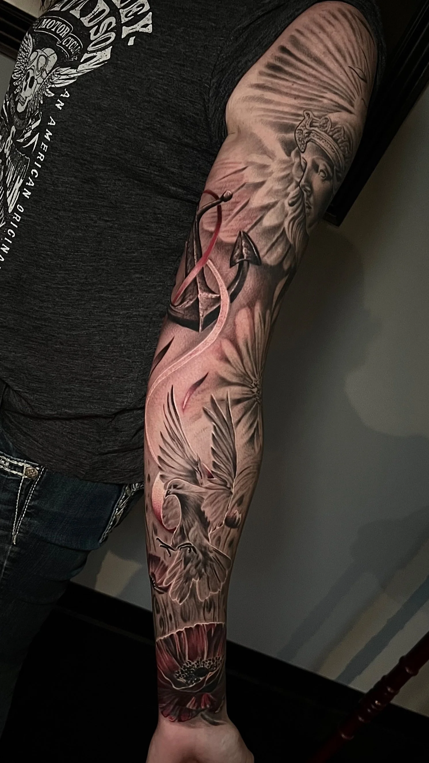 Black and gray tattoo sleeve featuring a woman with a crown, an anchor, a hummingbird, and a flower.