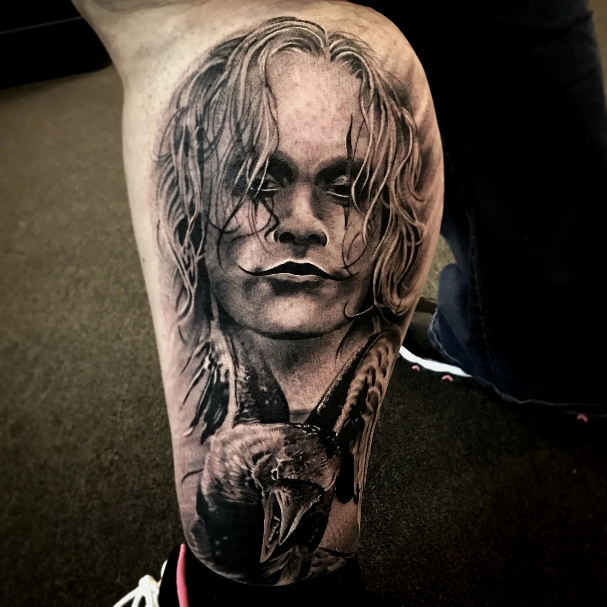 Black and gray realism tattoo of a woman's face with long, wavy hair and a serious expression, with a swan's head below her chin.