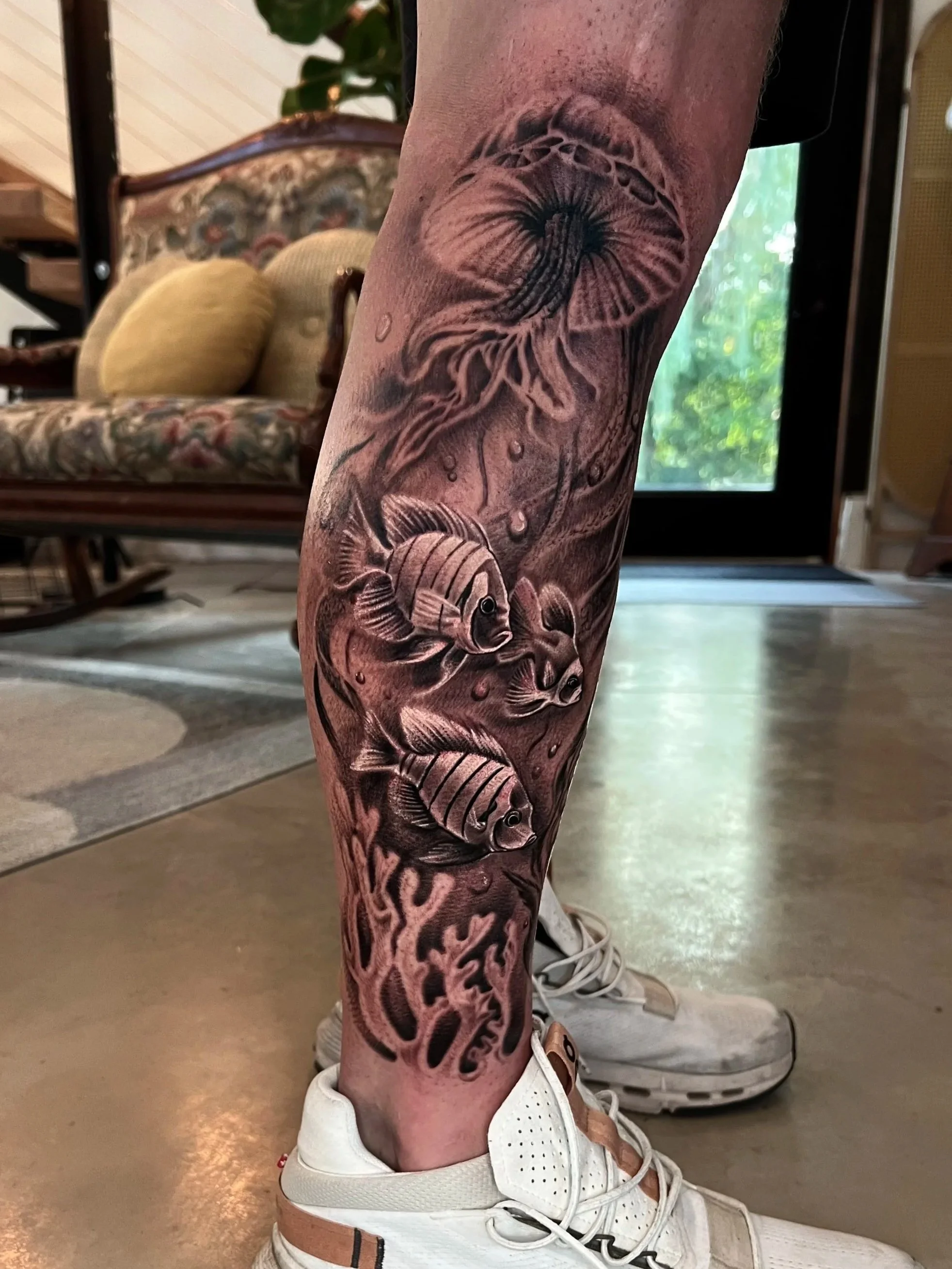 Tattoo of a jellyfish and three fish on a person's lower leg.