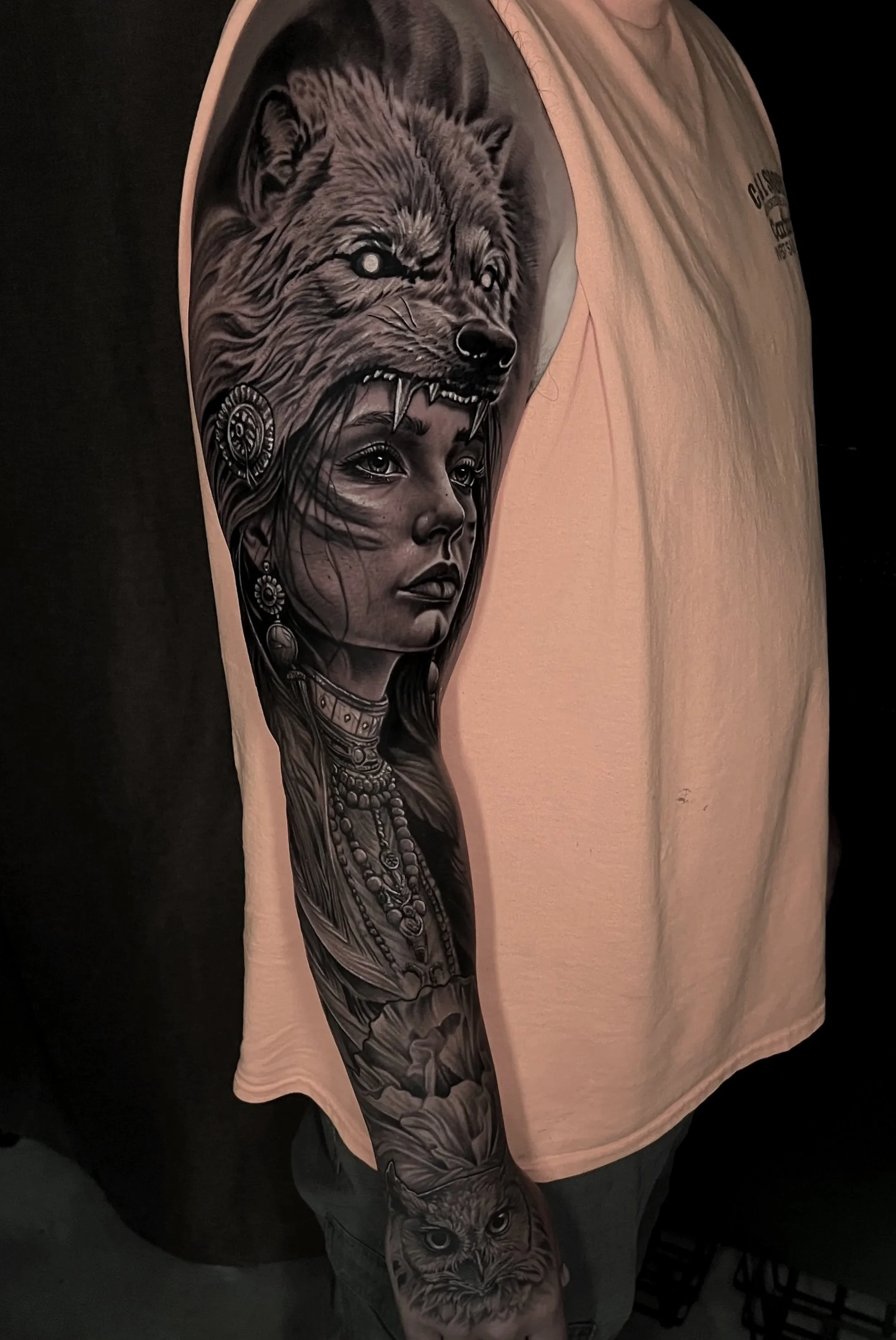 Tattoo sleeve featuring a wolf howling and a woman with traditional jewelry and face paint.