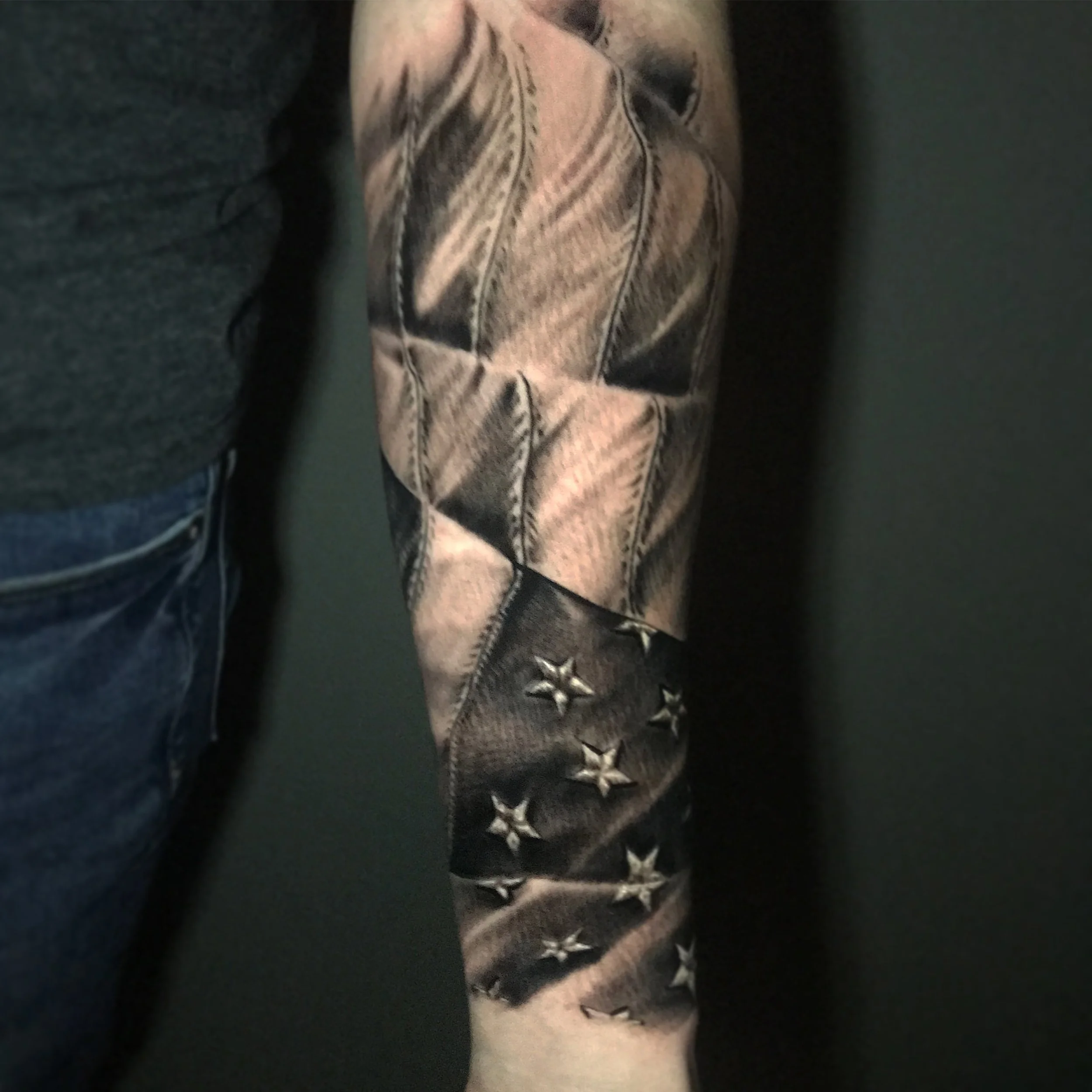 Close-up of a person's arm wearing a sleeve with a black and gray star pattern and metallic accents.