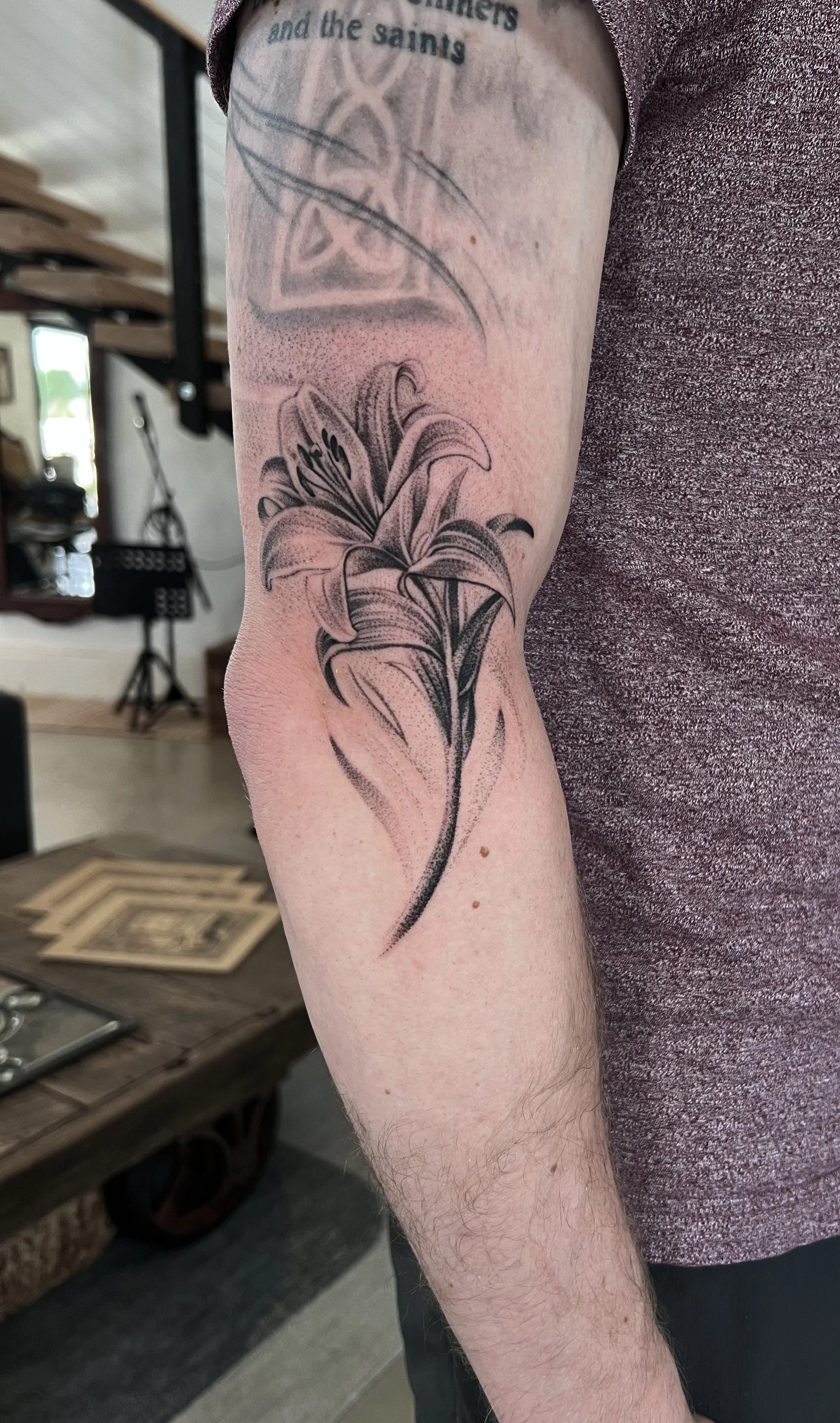 Black and gray tattoo of a detailed lily flower on a person's arm.
