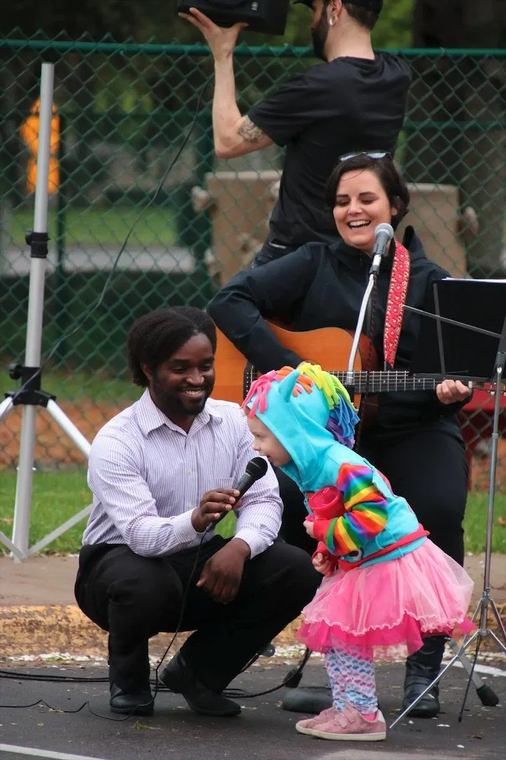 Elwyn Alexander Fraser Junior supporting a child singing at an event