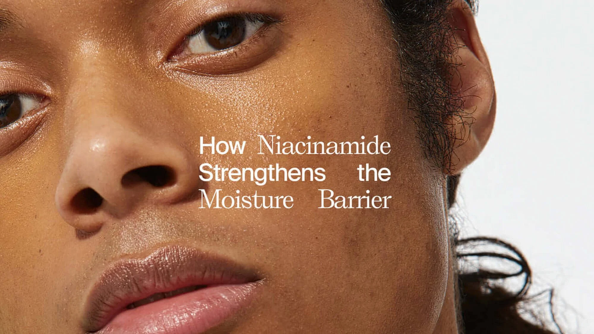 Close-up of woman’s face showing skin texture and pores, with overlaid text: "How Niacinamide Strengthens the Moisture Barrier".