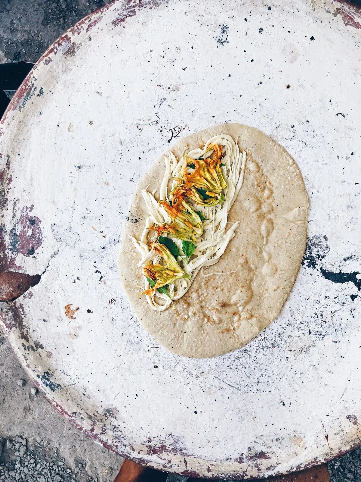 Tortilla con flor de calabaza y queso en una mesa de piedra