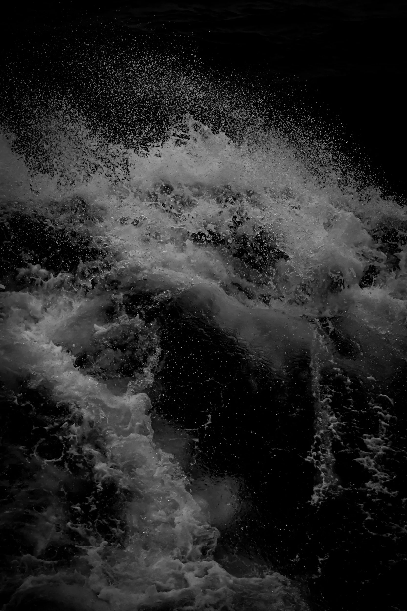 Dark sea or ocean water with white foamy waves and splashes, water appears to be turbulent or rough.