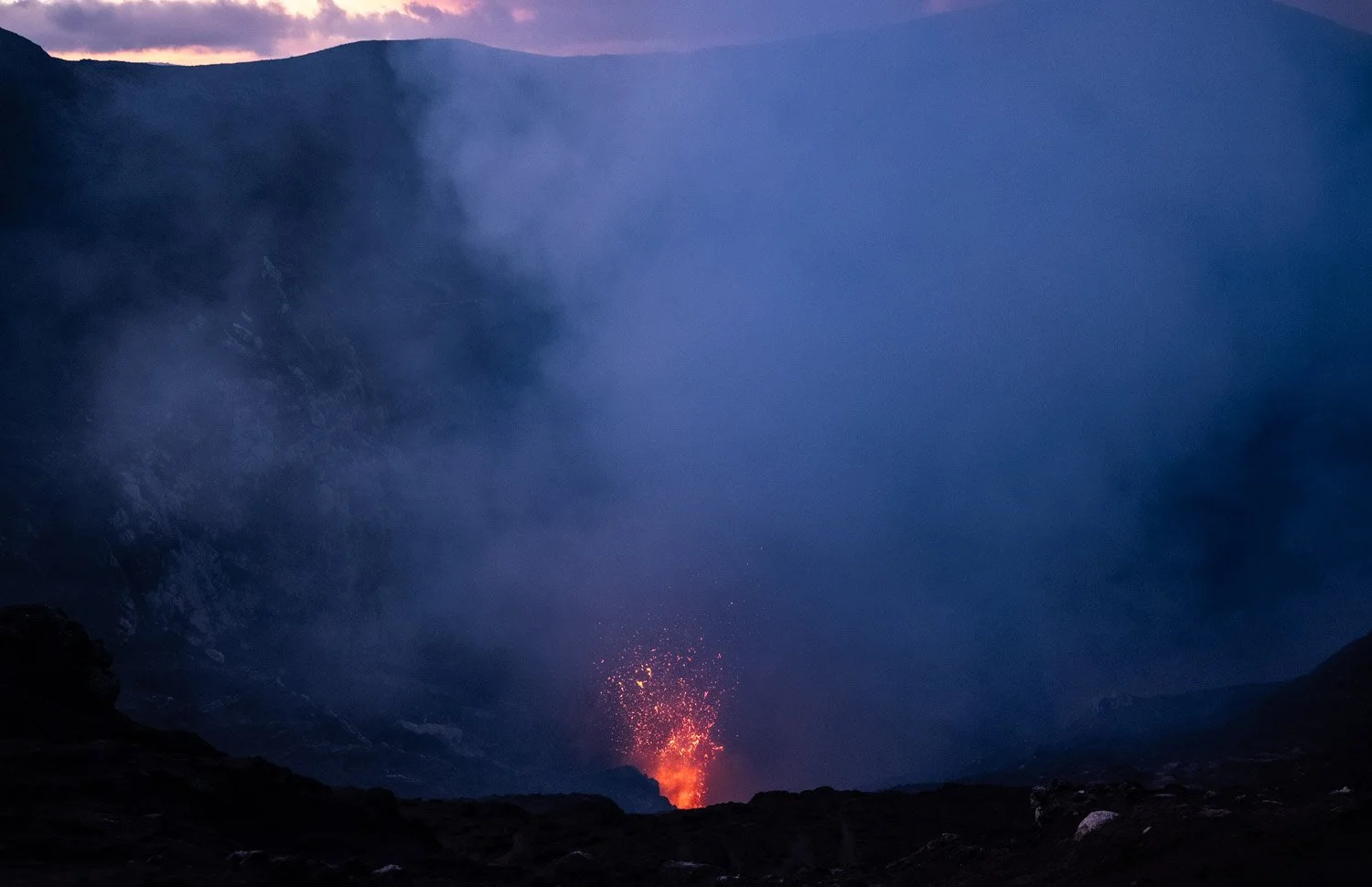 Eruption of a volcano with glowing lava and ash clouds rising into the sky.