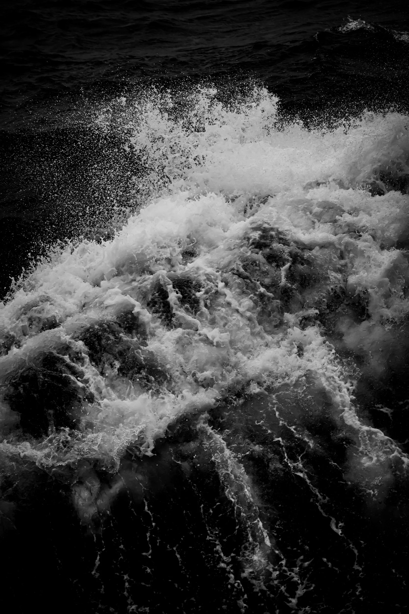 Black and white photo of ocean water with waves and sea spray.