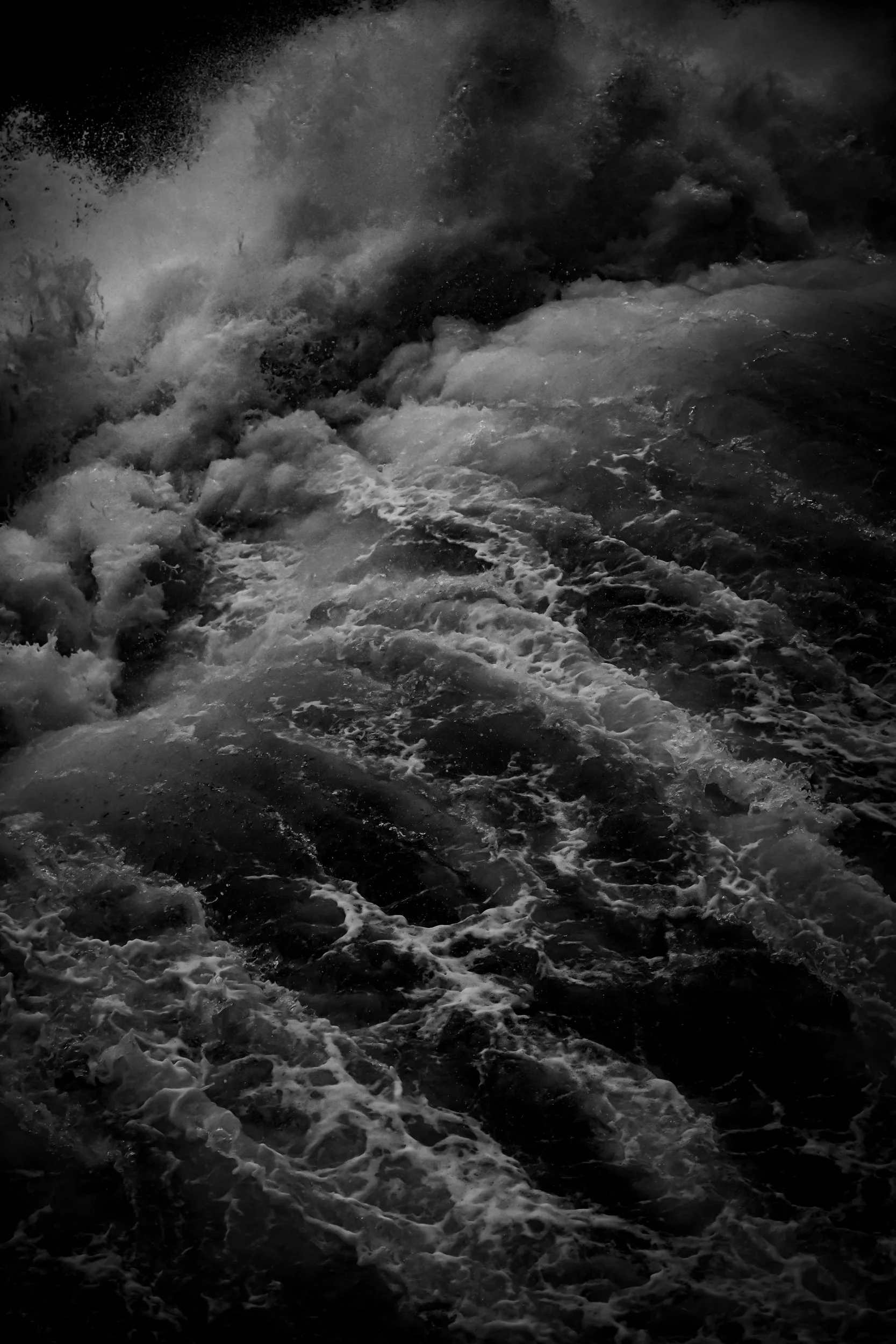 Black and white photo of ocean waves crashing and foaming.