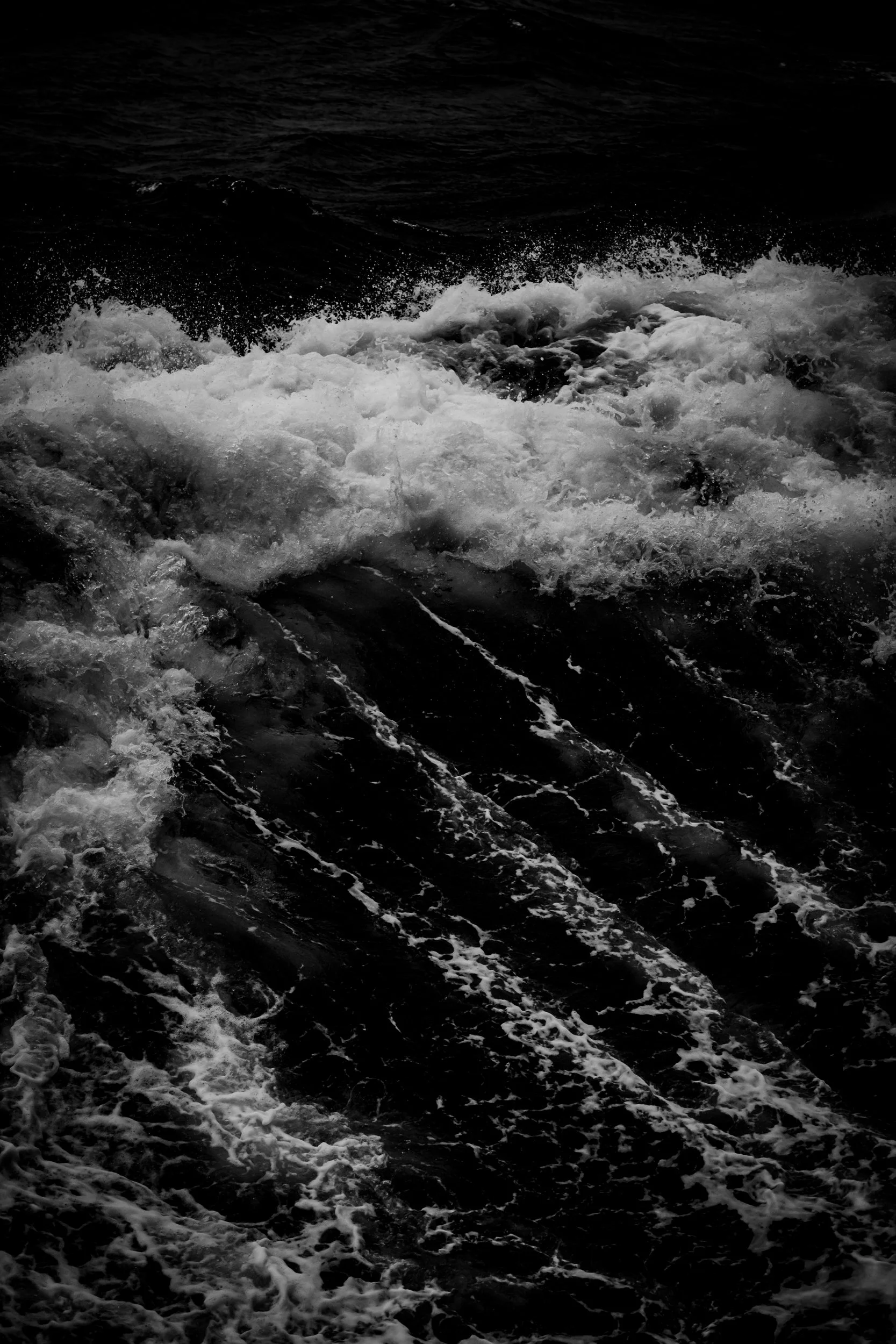 Black and white photo of ocean waves crashing and foaming in the water.