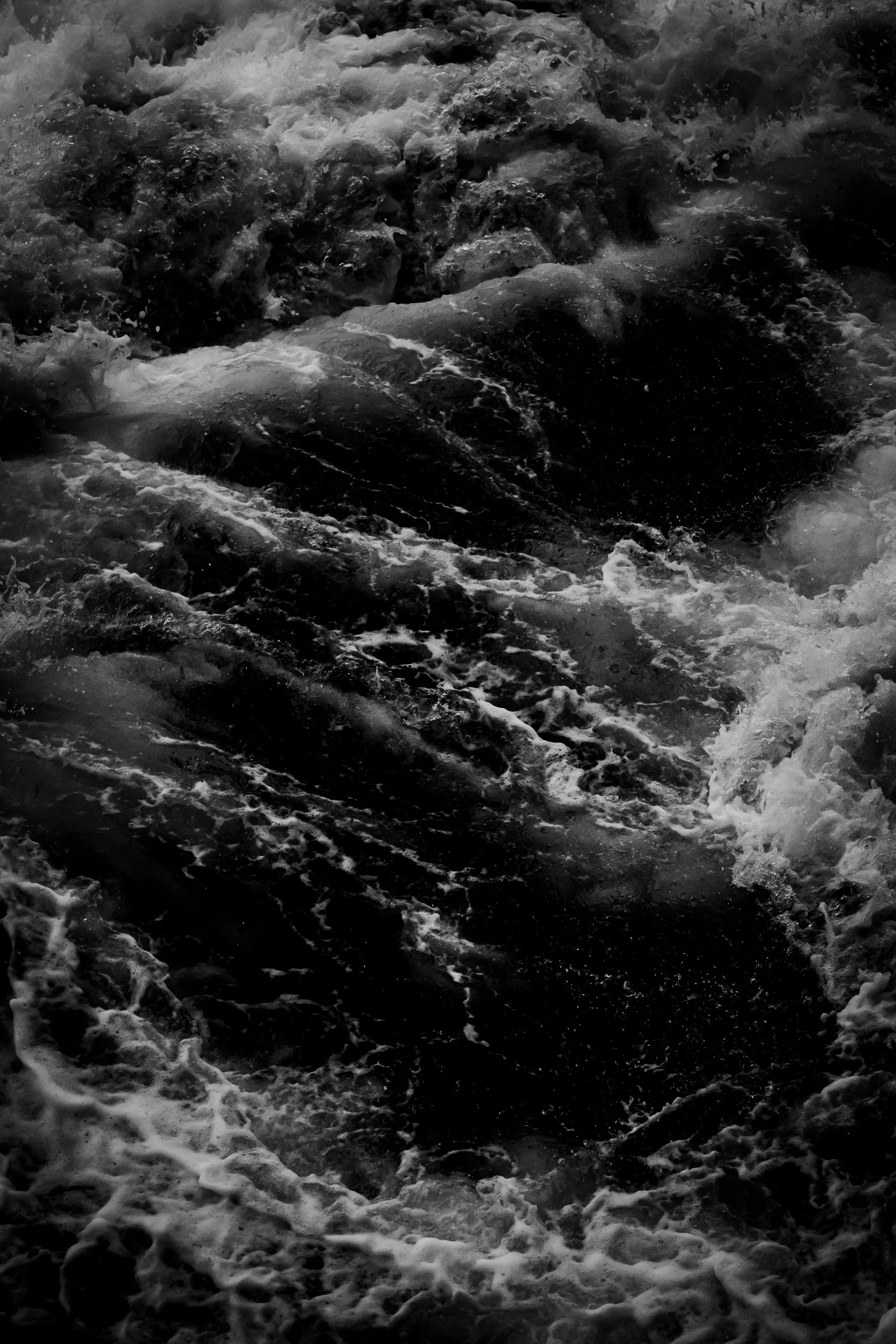 Black and white photograph of ocean waves crashing against rocks.