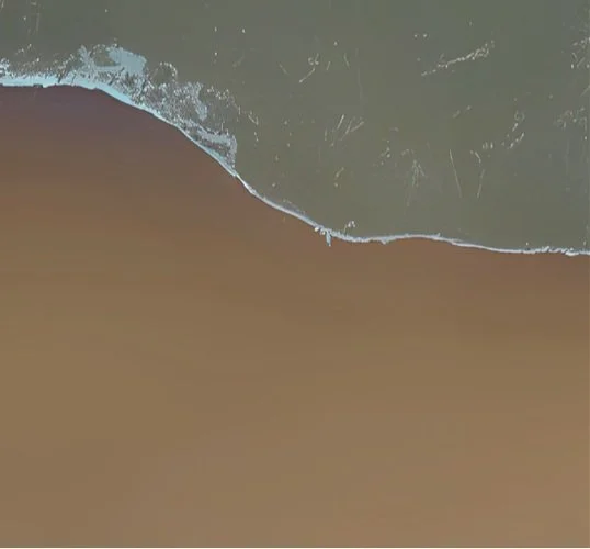 Aerial view of a beach showing the shoreline where ocean waves meet sandy shore.