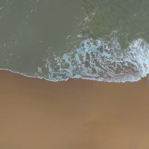 View of ocean waves washing onto sandy beach