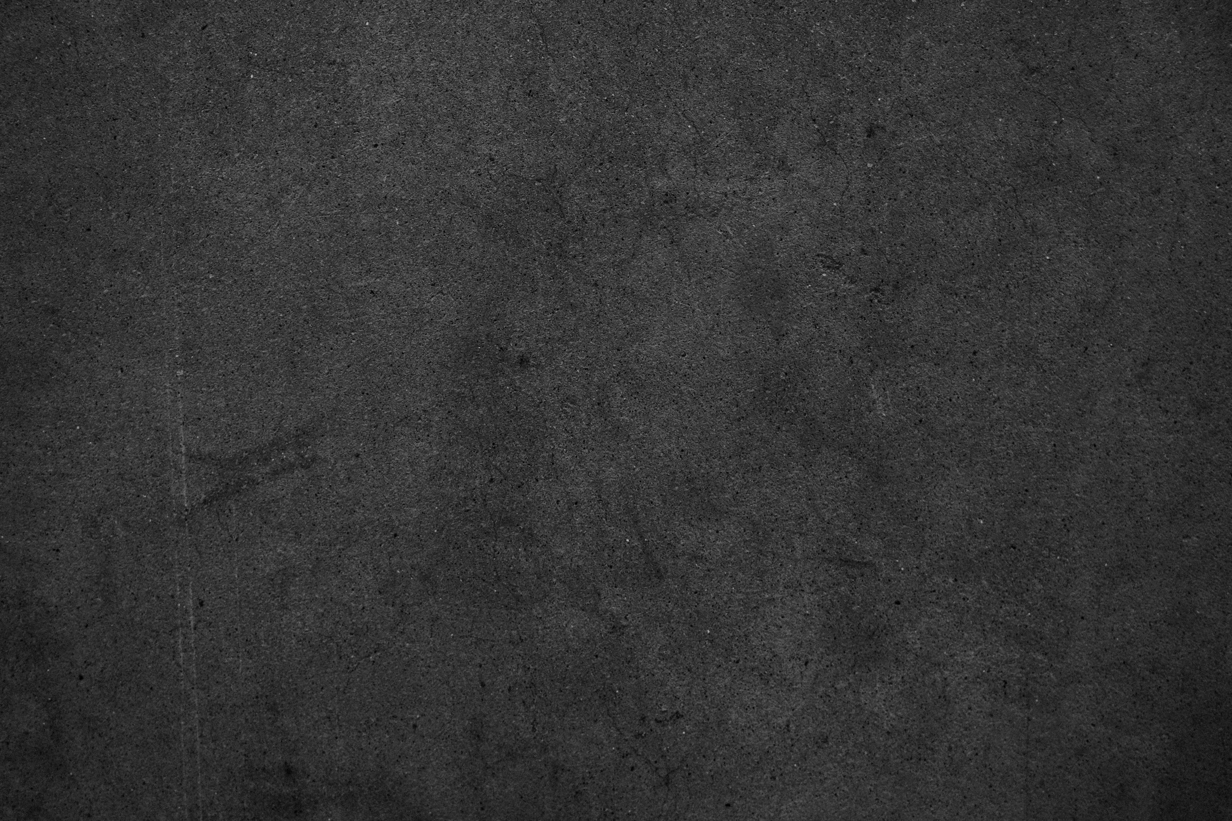 A black, textured surface resembling asphalt or concrete.