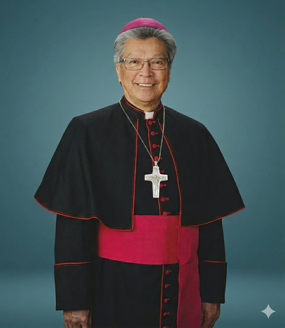 A person dressed in religious clerical attire, wearing glasses, a black and red robe, and a large cross necklace, smiling at the camera against a gray background.