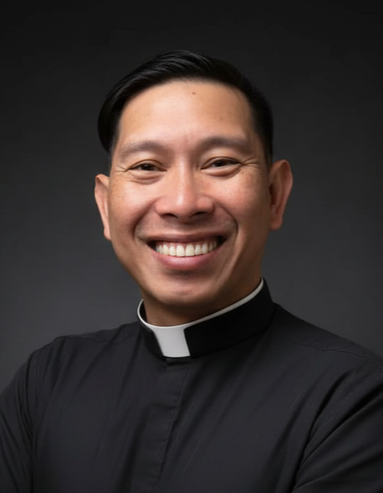 Portrait of a smiling man wearing a black clergy shirt with a white collar against a dark background.